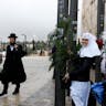 A Jewish man walks past a man dressed as Santa Claus and Russian Orthodox nuns in Jerusalem's Old City. (Photo by Gali TIbbon/ AFP via Getty Images.) A Jewish man walks past a man dressed as Santa Claus and Russian Orthodox nuns in Jerusalem's Old City. (Photo by Gali TIbbon/ AFP via Getty Images.)