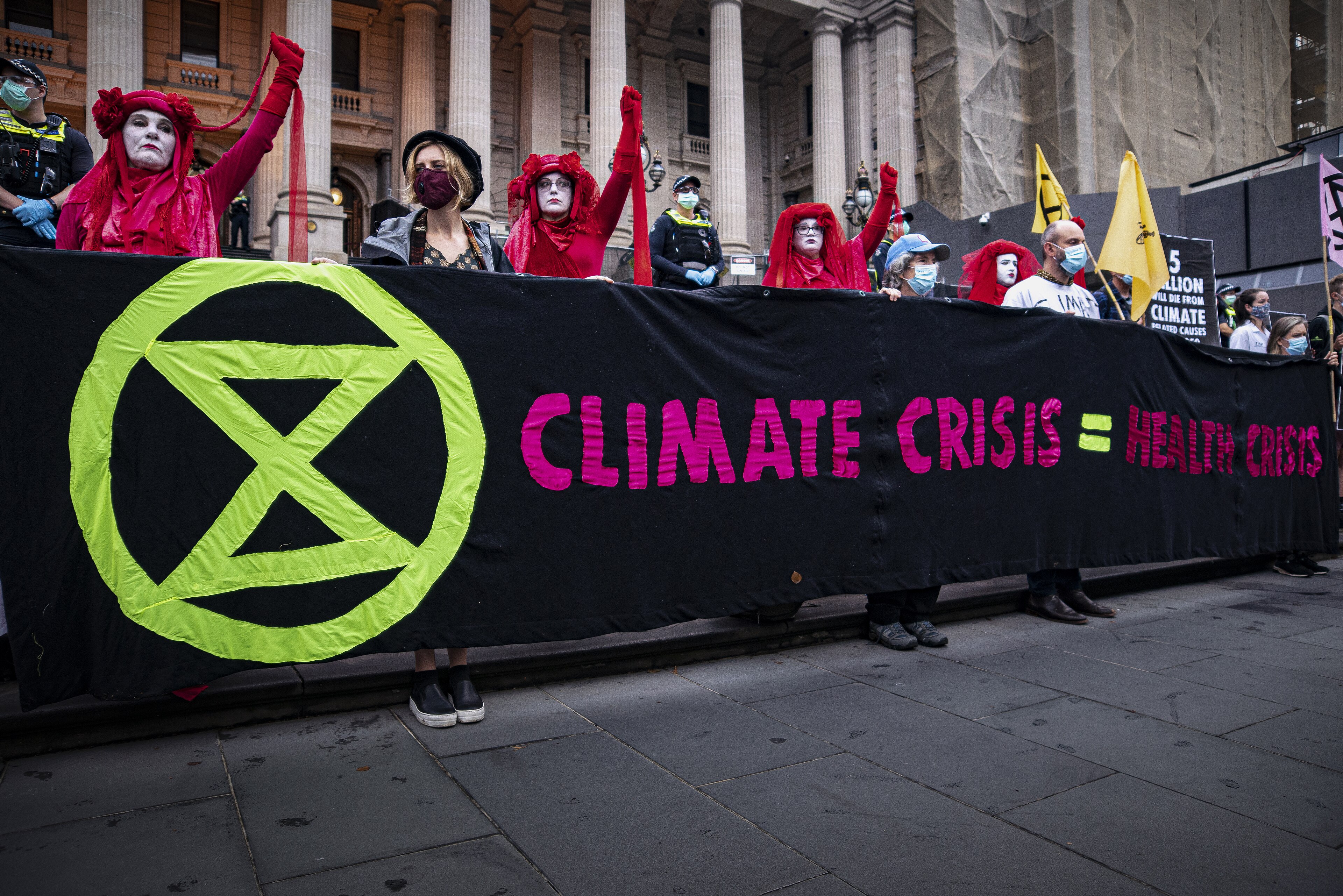Healthcare workers die-in at the front of the Victorian Parliament, part of Day 1 of Extinction Rebellion's Autumn Rebellion in Melbourne. Wikimedia.