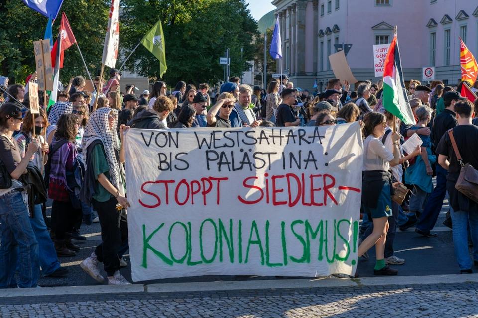 A Large Crowd of Anti Zionist Protesters in Berlin With A Sign in German that Says Stop Settler Colonialism (Shutterstock) A Large Crowd of Anti Zionist Protesters in Berlin With A Sign in German that Says Stop Settler Colonialism (Shutterstock)