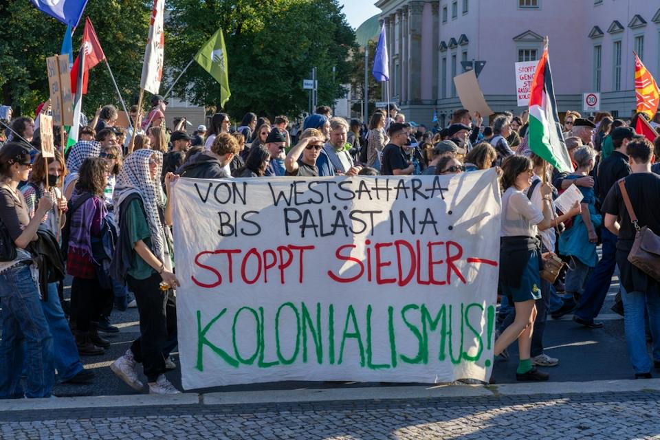 A Large Crowd of Anti Zionist Protesters in Berlin With A Sign in German that Says Stop Settler Colonialism (Shutterstock)