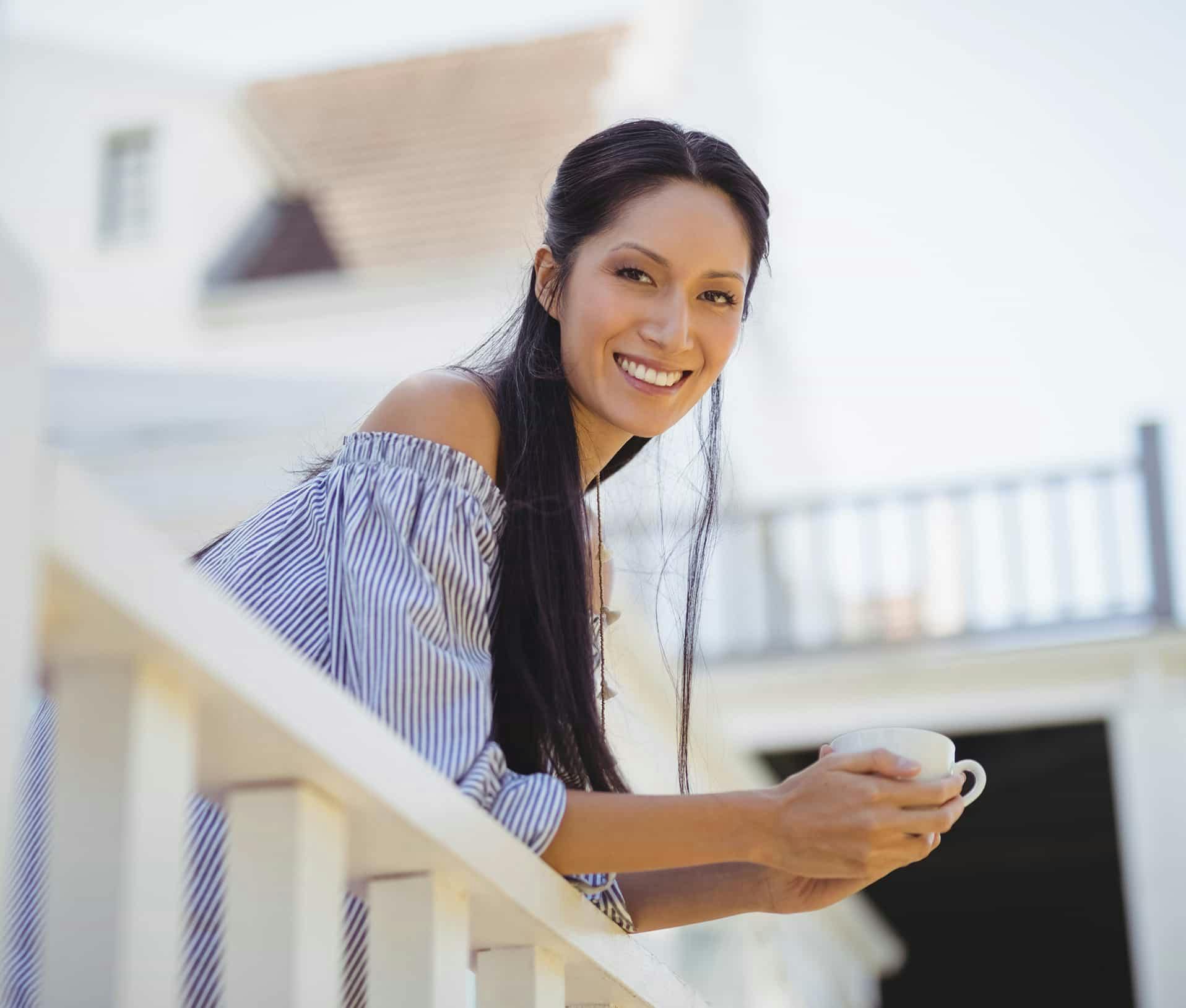 Woman leaning on railing smiling outside