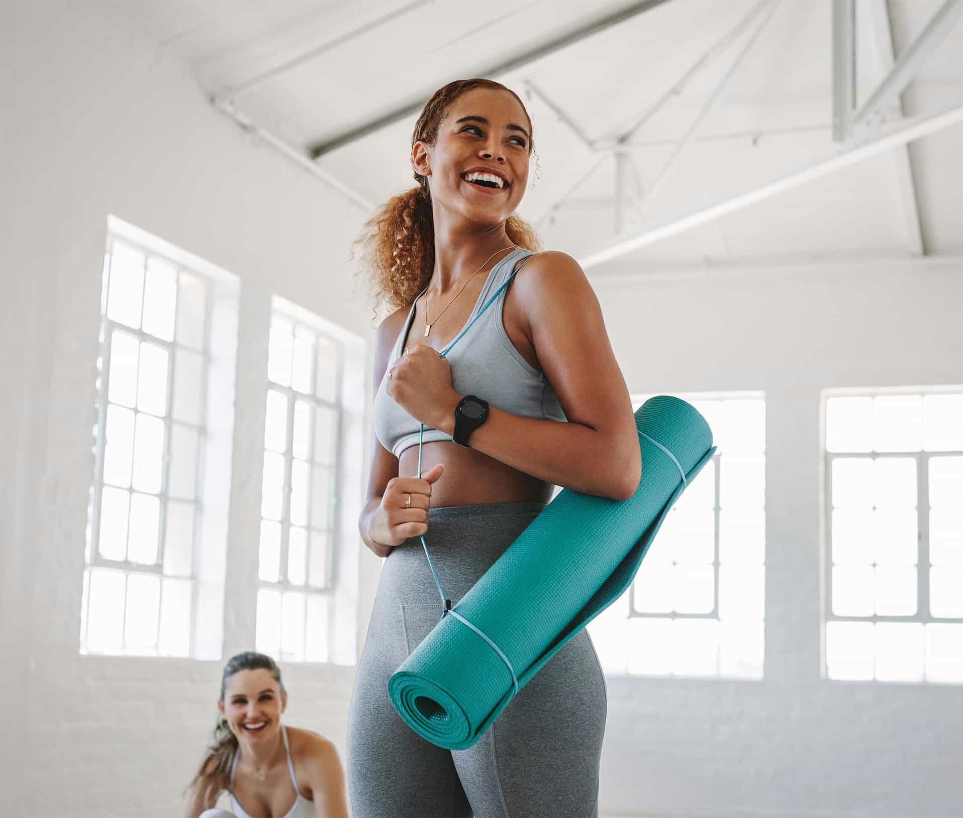 Woman holding yoga mat smiling
