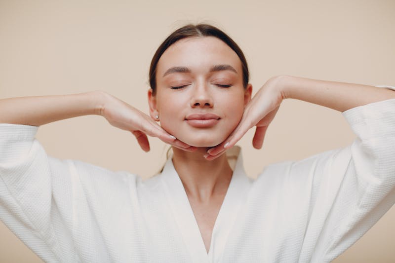 woman in white robe with beautiful skin and framing face with hands