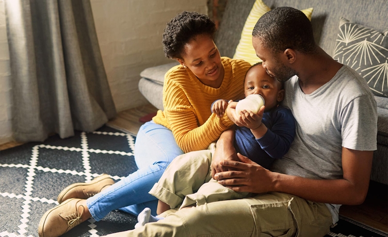 mom and dad bottle feeding their baby