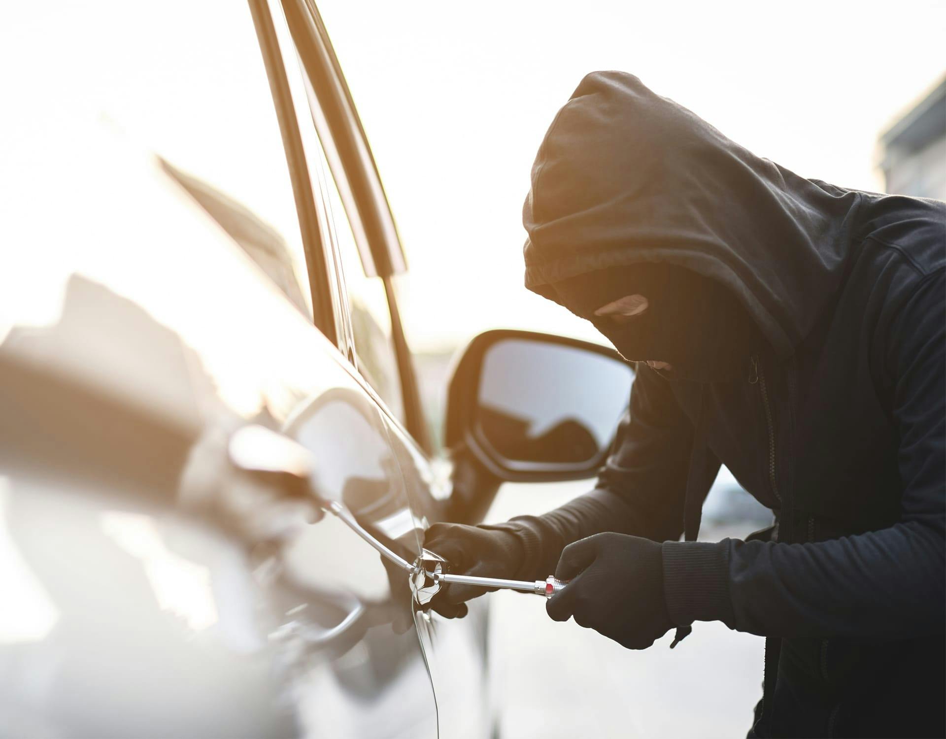 masked man breaking into a car