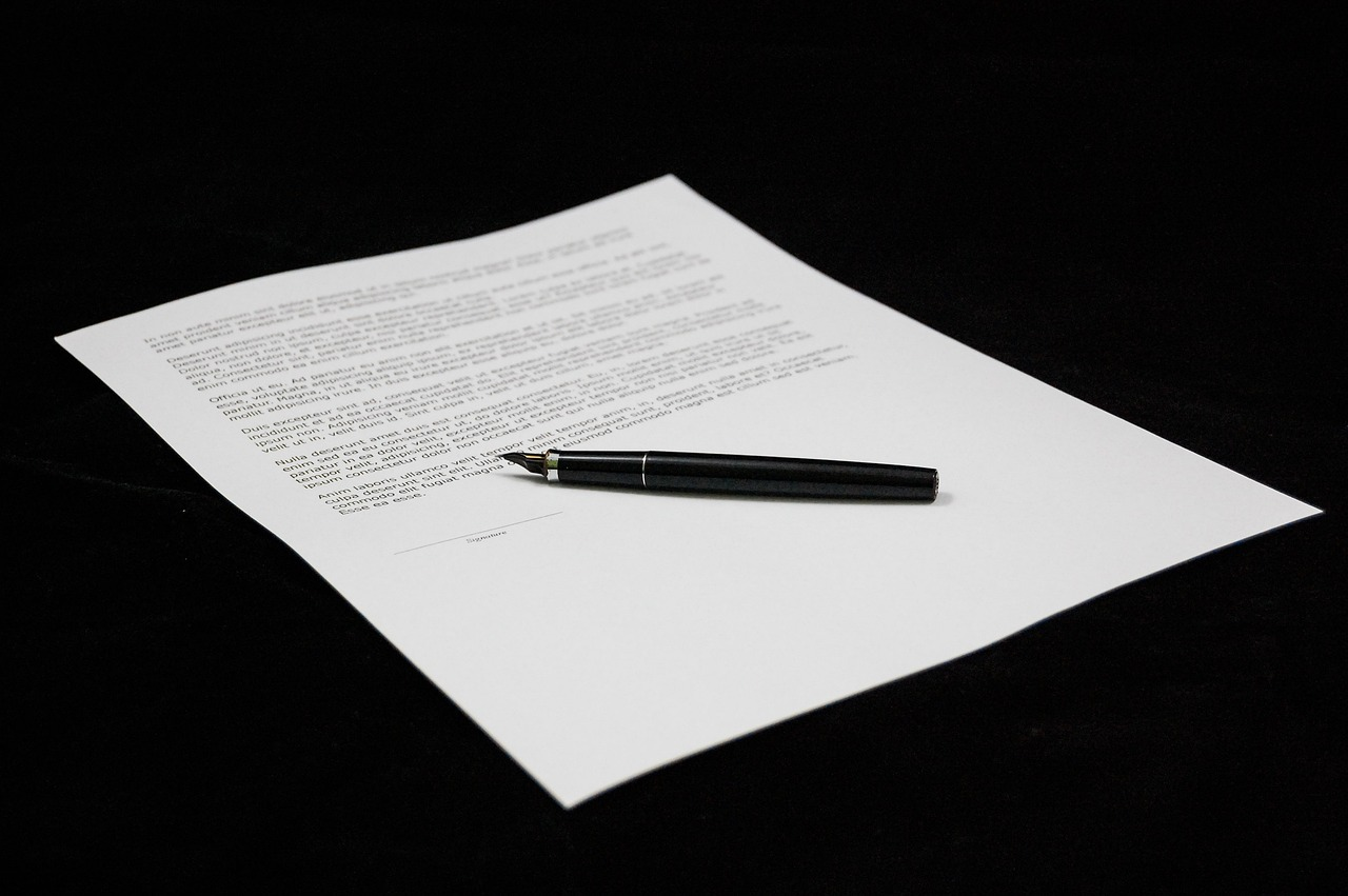 This image shows a close-up of a document on white paper with printed text and a black pen on top of it, ready for signing.