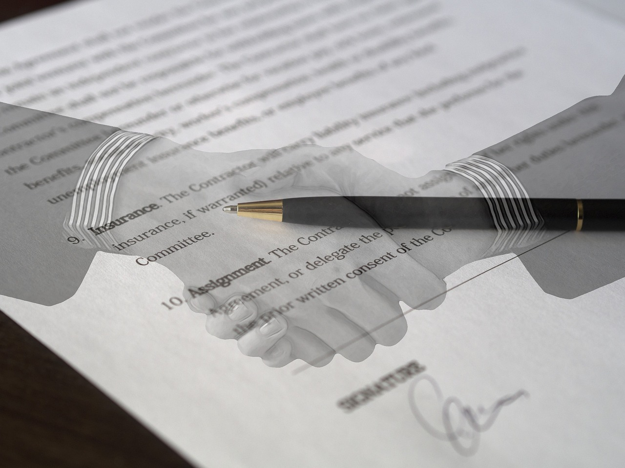 Image of a handshake overlaying a signed insurance contract with a pen placed on top.