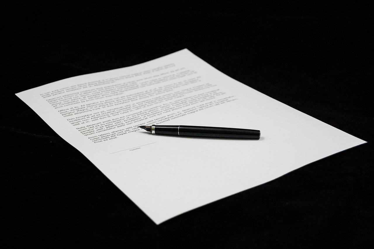 A document with text on a white sheet of paper, placed on a black background, with a black fountain pen resting on top, near the signature line.