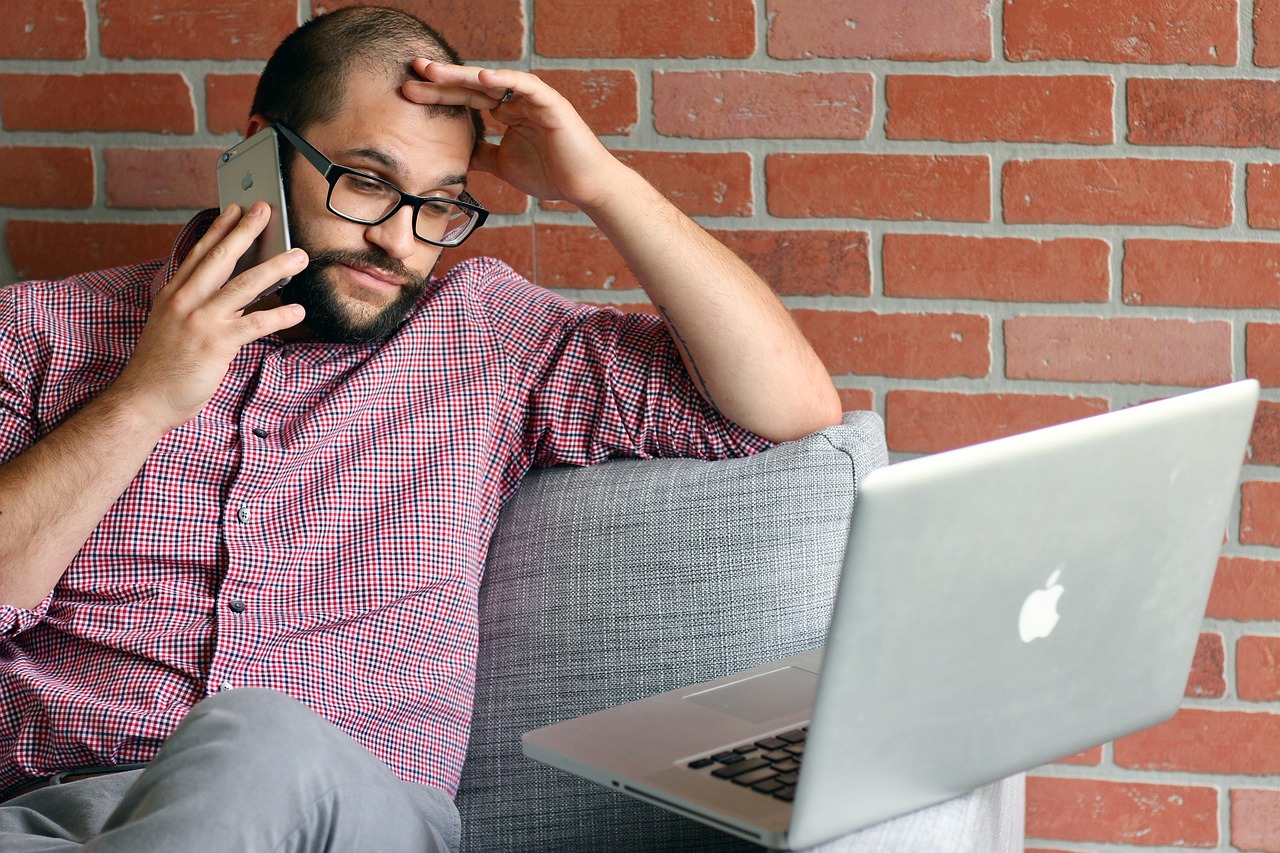  A man looking frustrated while sitting at a laptop.