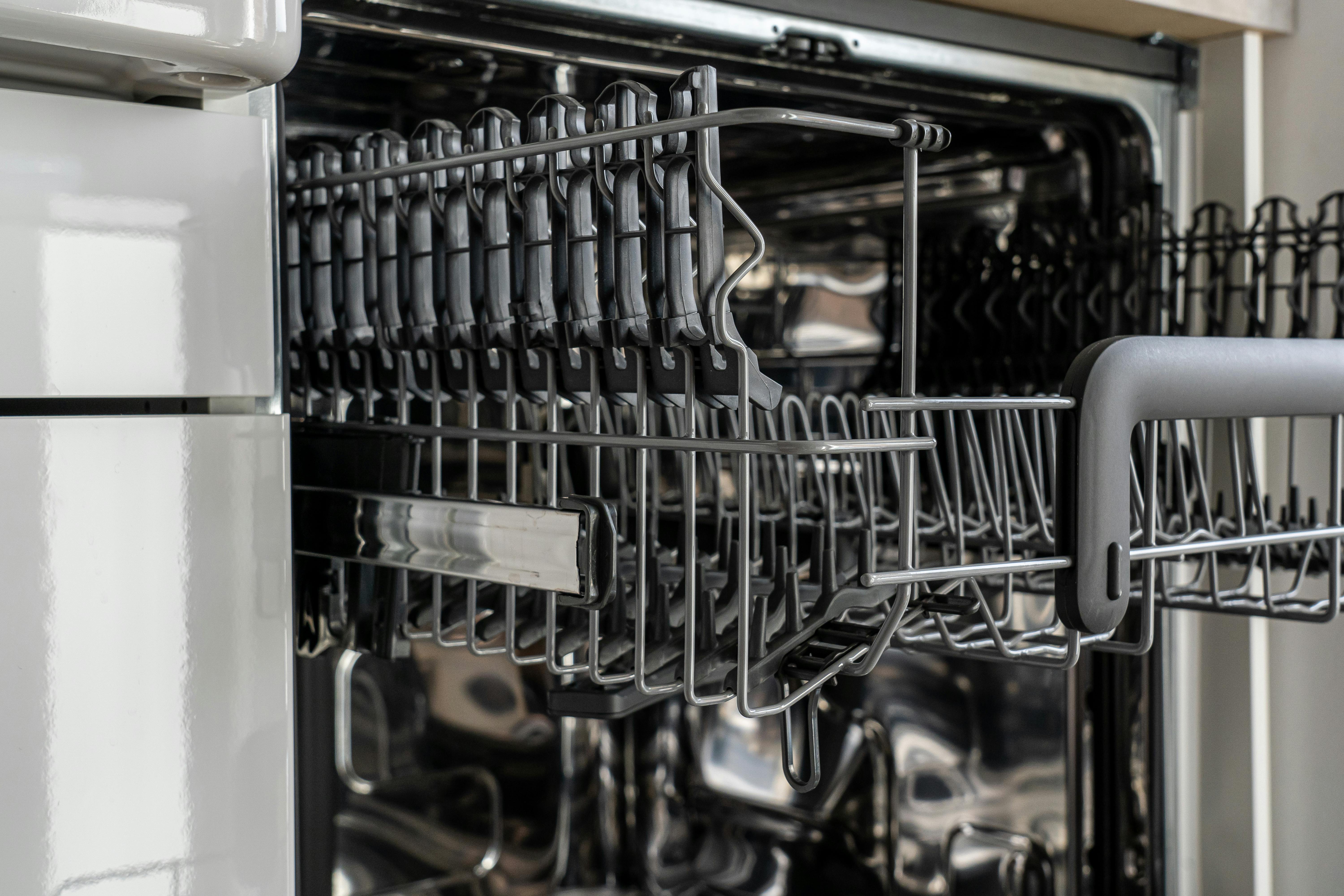 Open dishwasher with extended racks and an empty silverware basket, showing the interior and loading space.