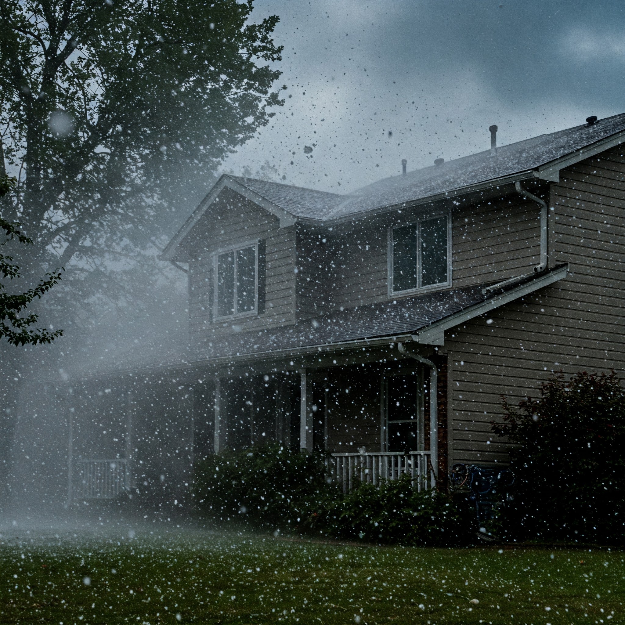 Hailstorm hitting a house with heavy rain and hail falling on the roof and yard.