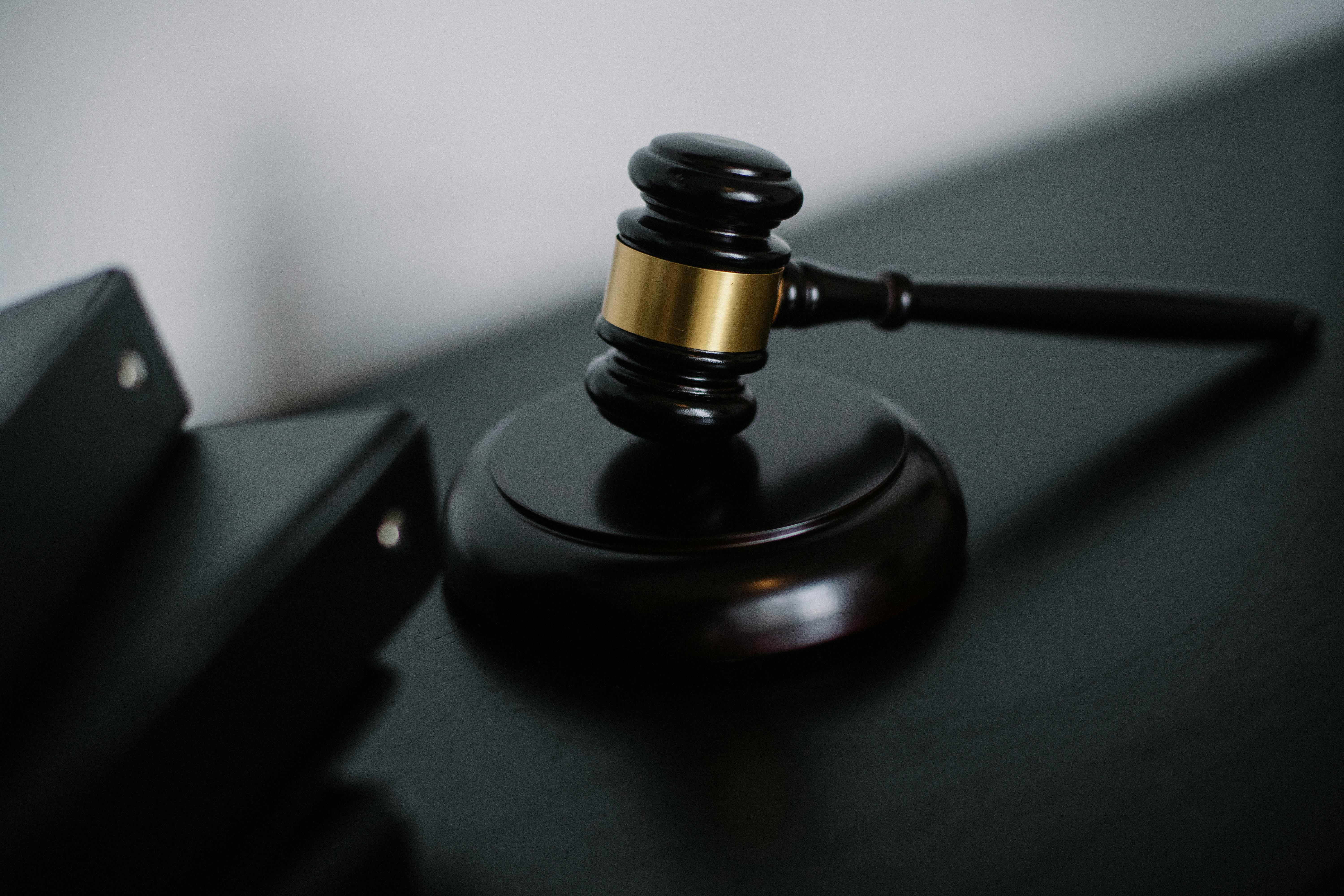 Close-up of a judge's gavel resting on a wooden table next to black binders.