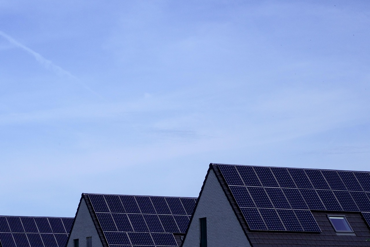 Rooftops of houses with solar panels under a clear blue sky.