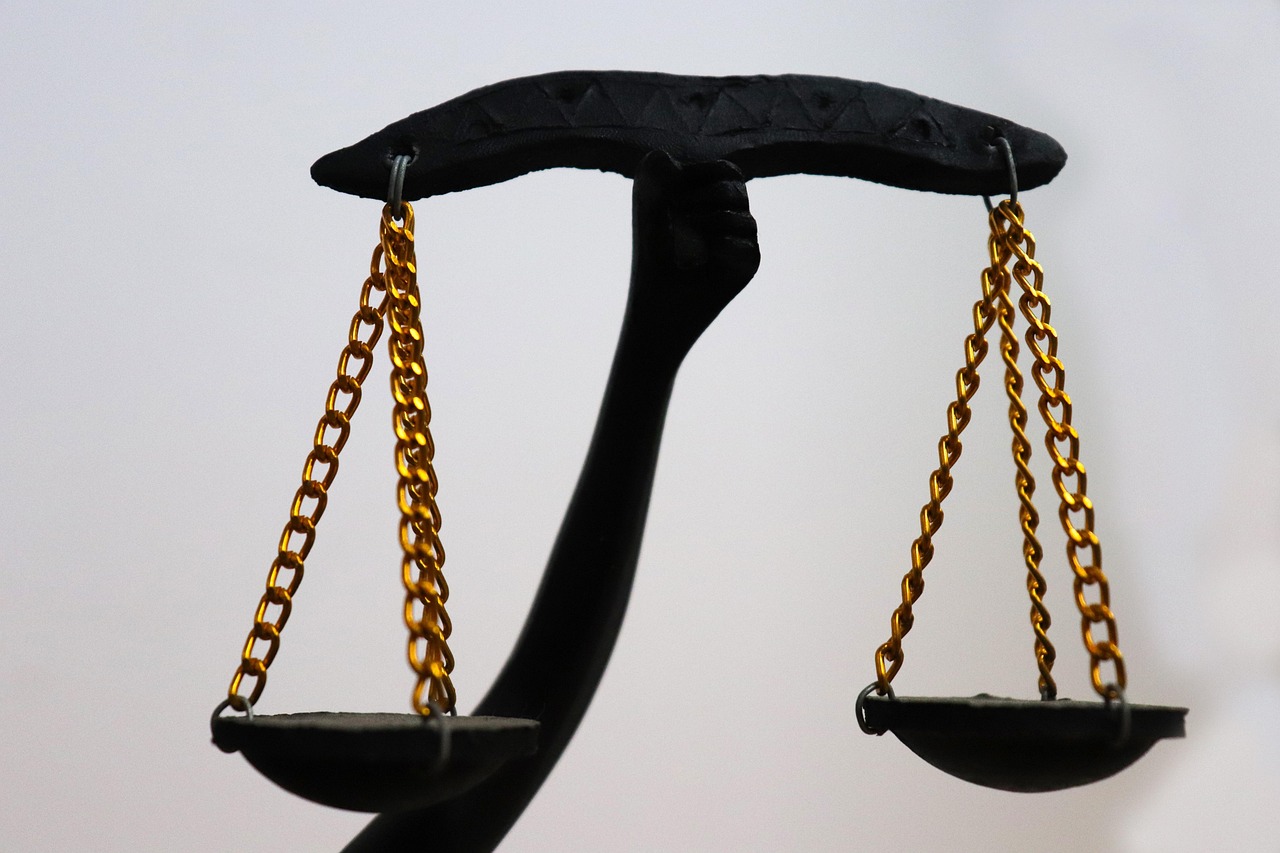 A black balance scale with gold chains, symbolizing justice.