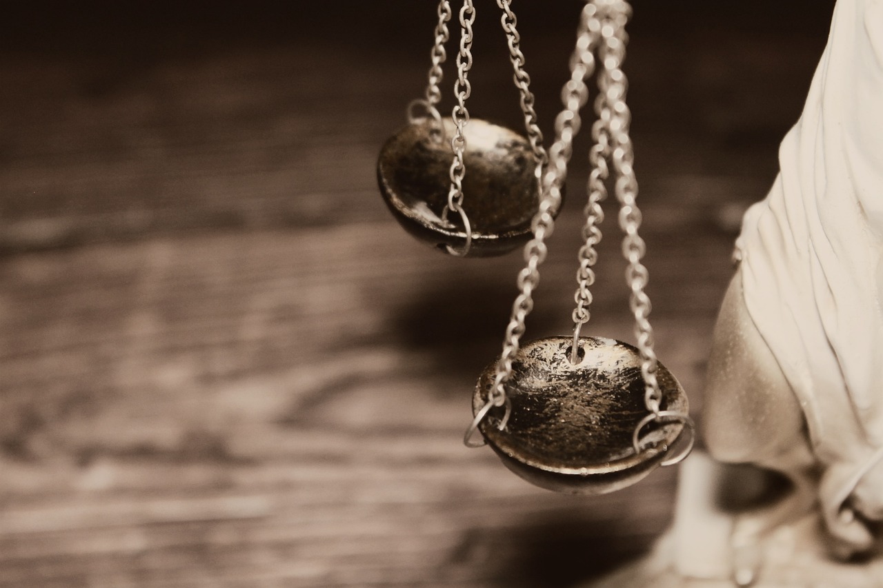 A close-up image of the scales of justice, showing two metal pans hanging from chains, symbolizing fairness and balance in the legal system.