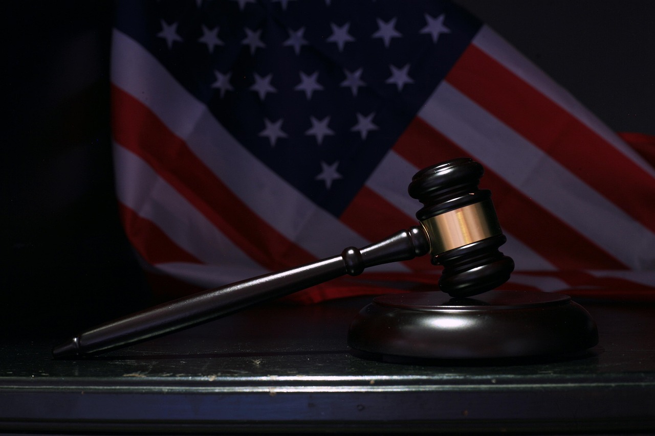 Judge’s gavel resting on a block with the American flag in the background, symbolizing justice and U.S. law.
