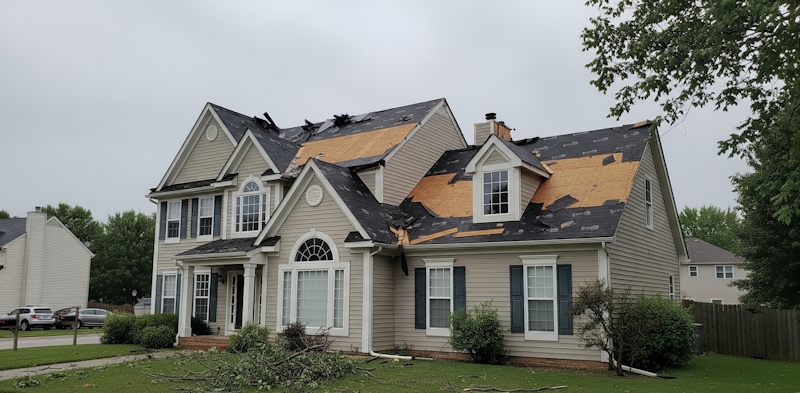 House with severe roof damage; missing shingles and exposed wood after a storm.