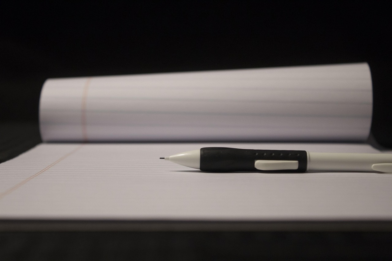Close-up of a mechanical pencil resting on a blank, lined notepad.