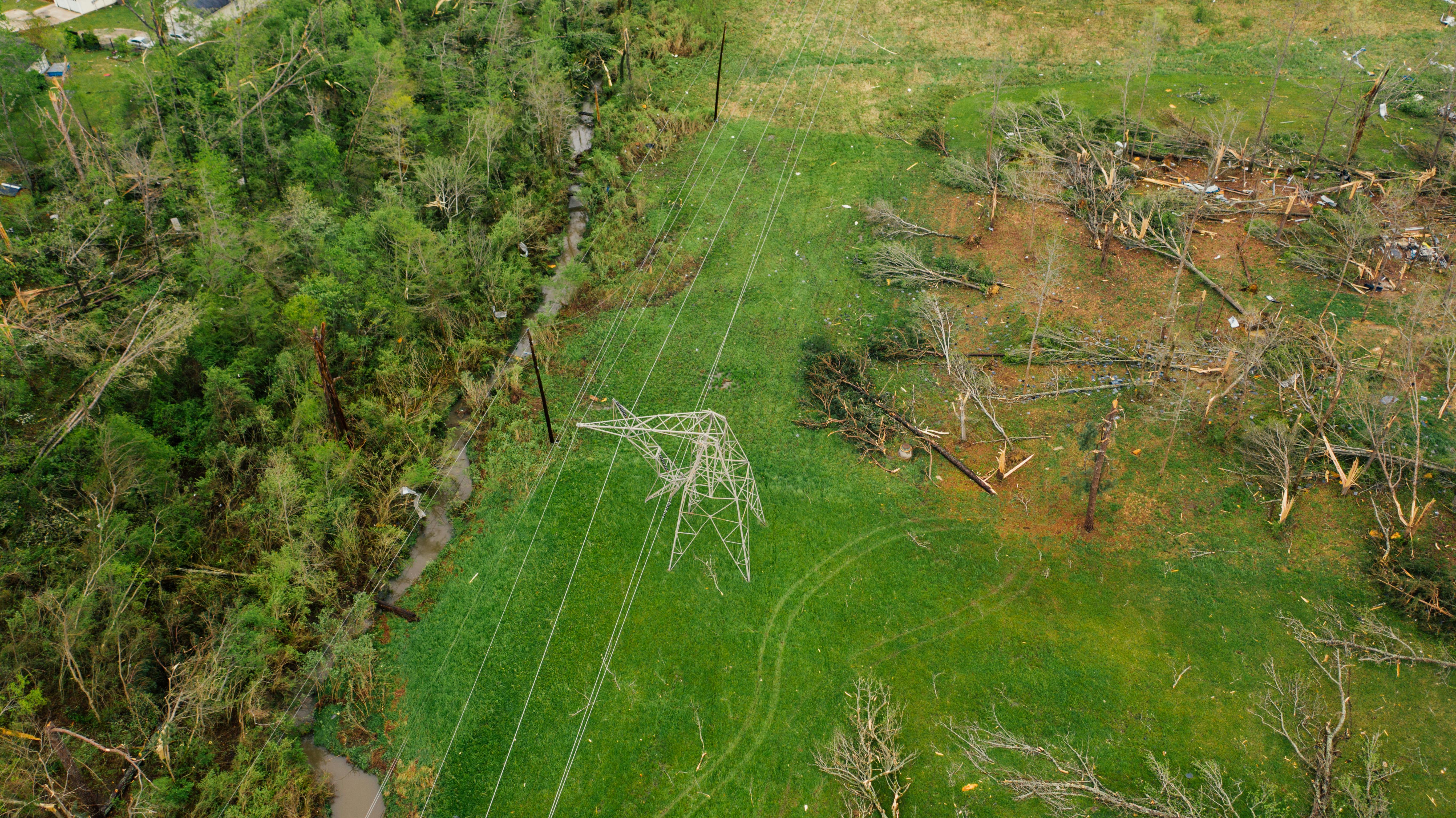  Aerial view of tornado damage showing a collapsed power line tower and snapped trees.
