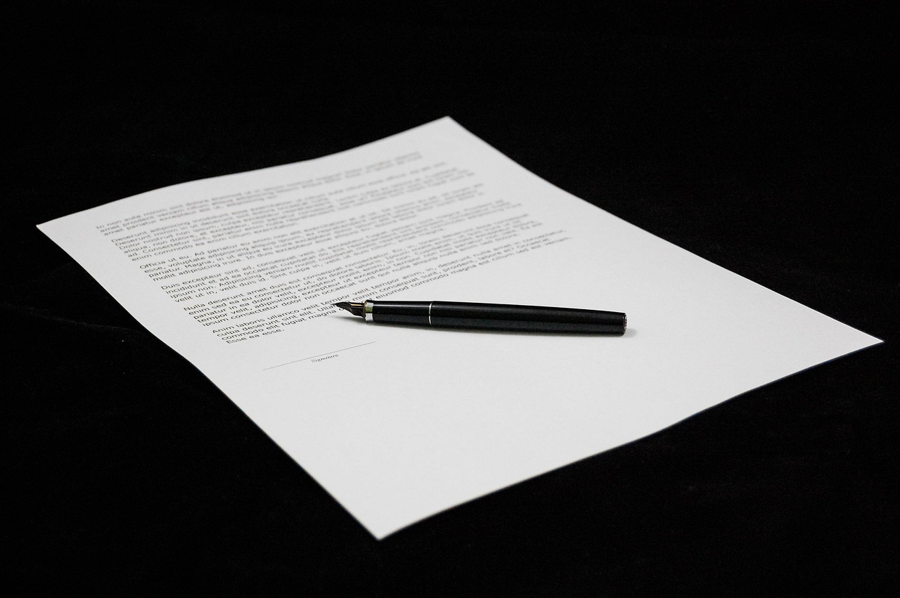 Contract document with a black pen placed on top, ready for signature.