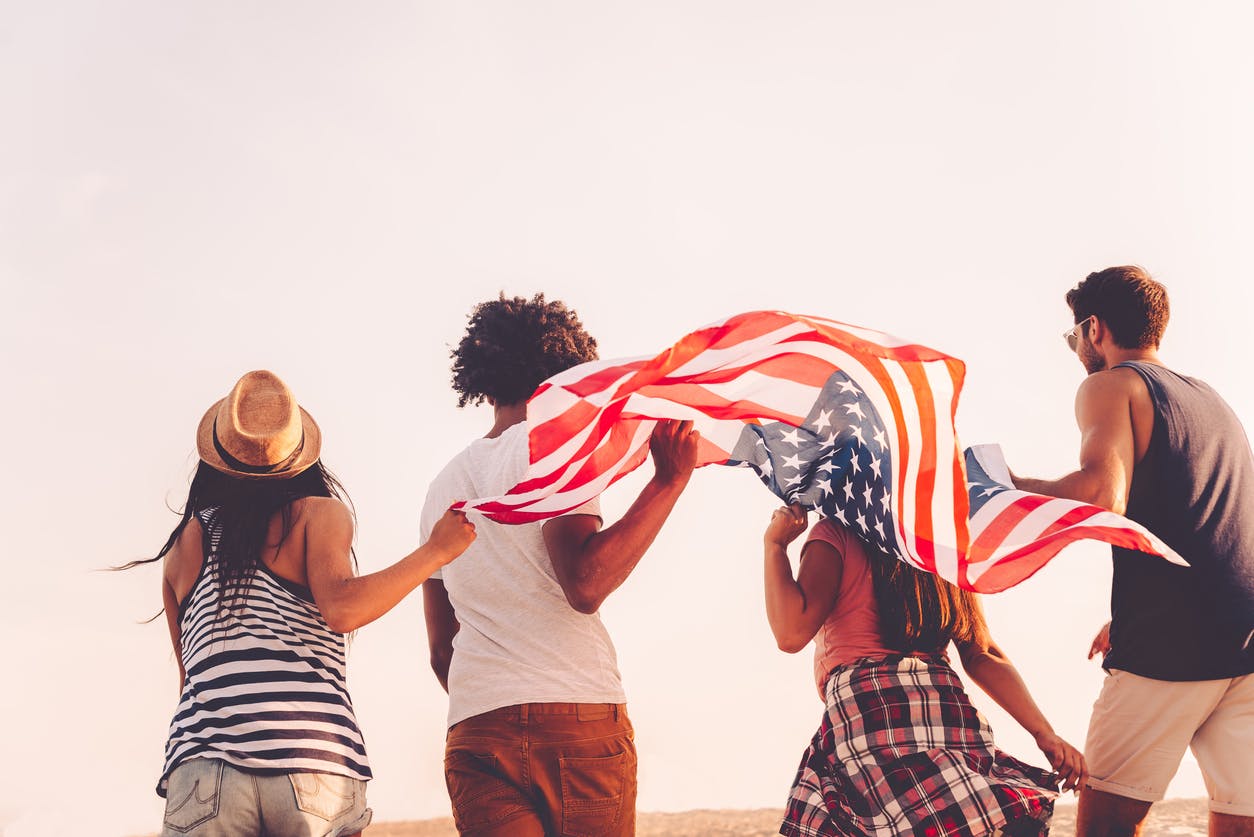 Diverse group of people running with the american flag