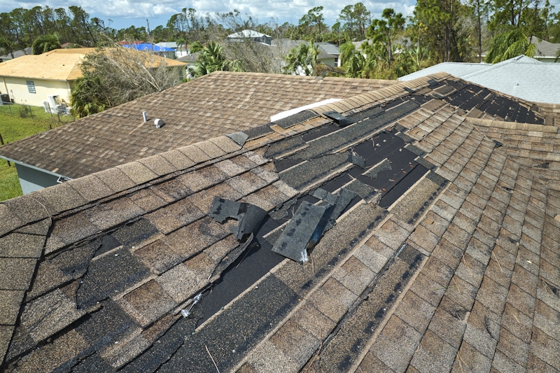 Wind damaged house roof with missing shingles