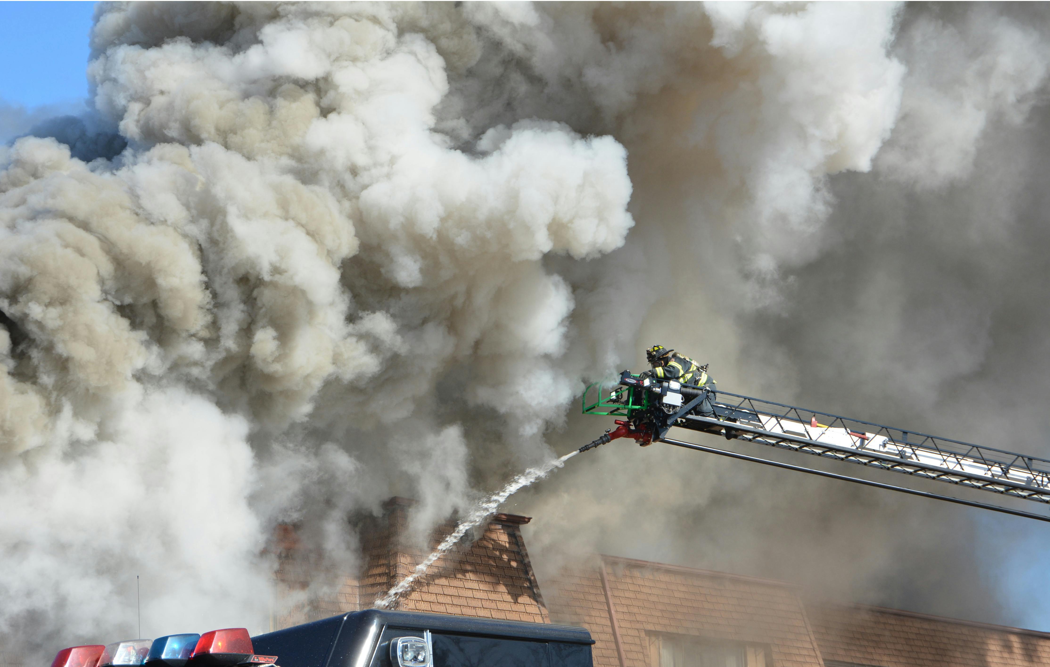 Firefighters spraying water on a house fire with heavy smoke