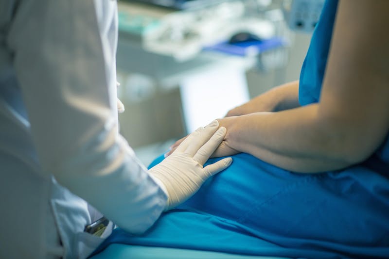 Patient speaking with a doctor during a medical consultation about breast surgery risks and possible mesh implant complications.