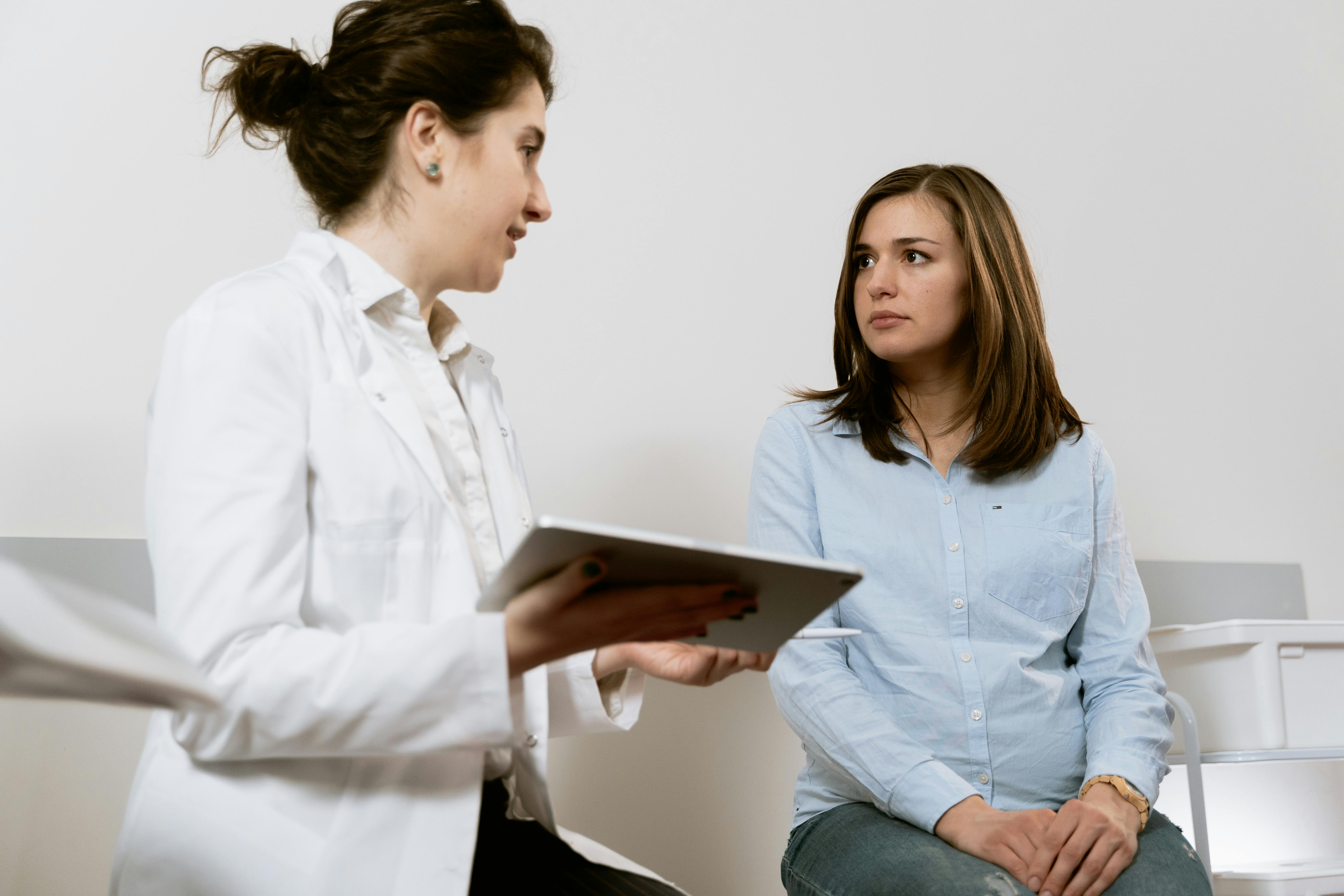 Doctor performing a clinical examination on a patient before or after breast surgery to evaluate possible complications.