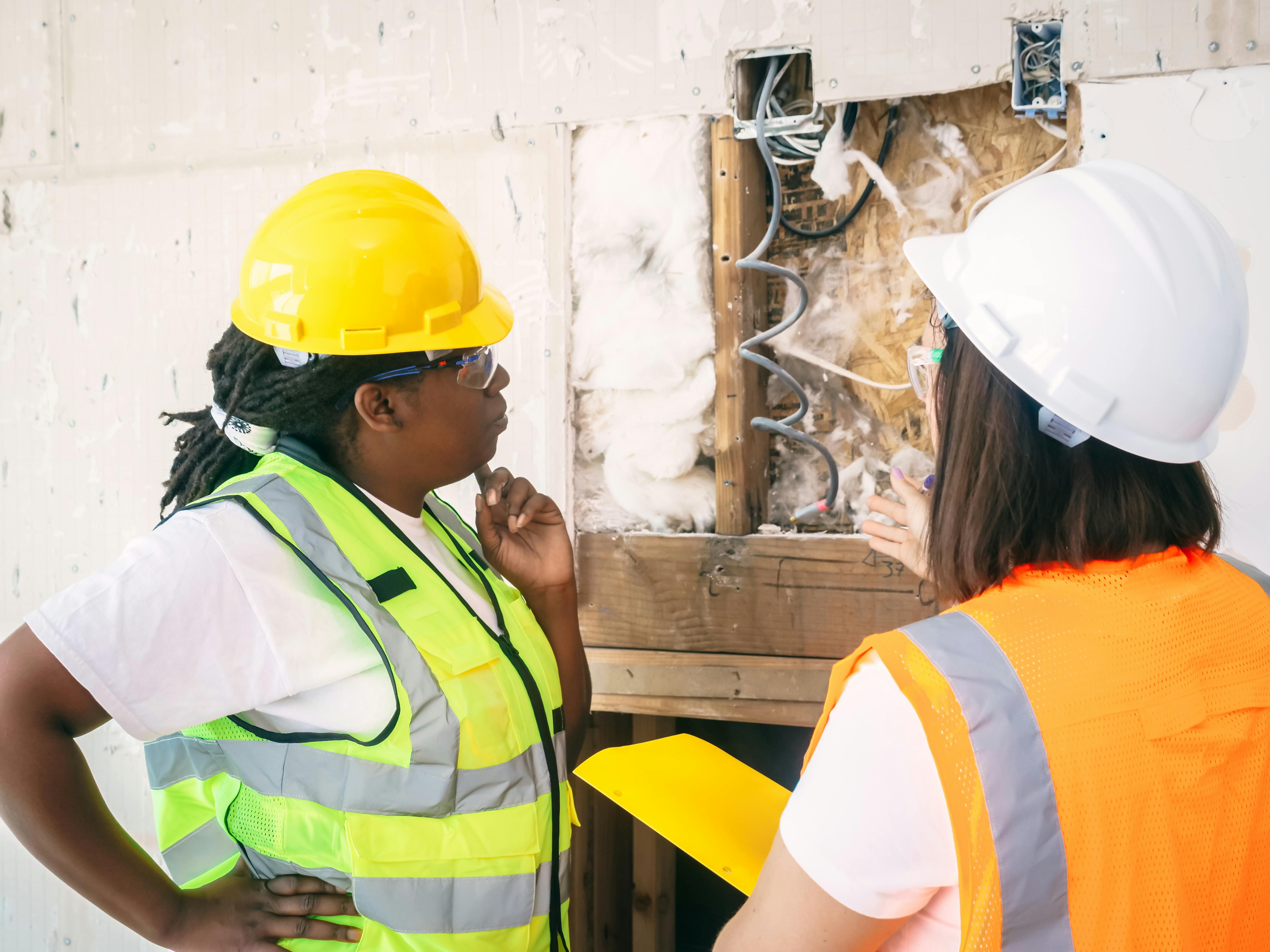 Construction workers looking at wall of a building