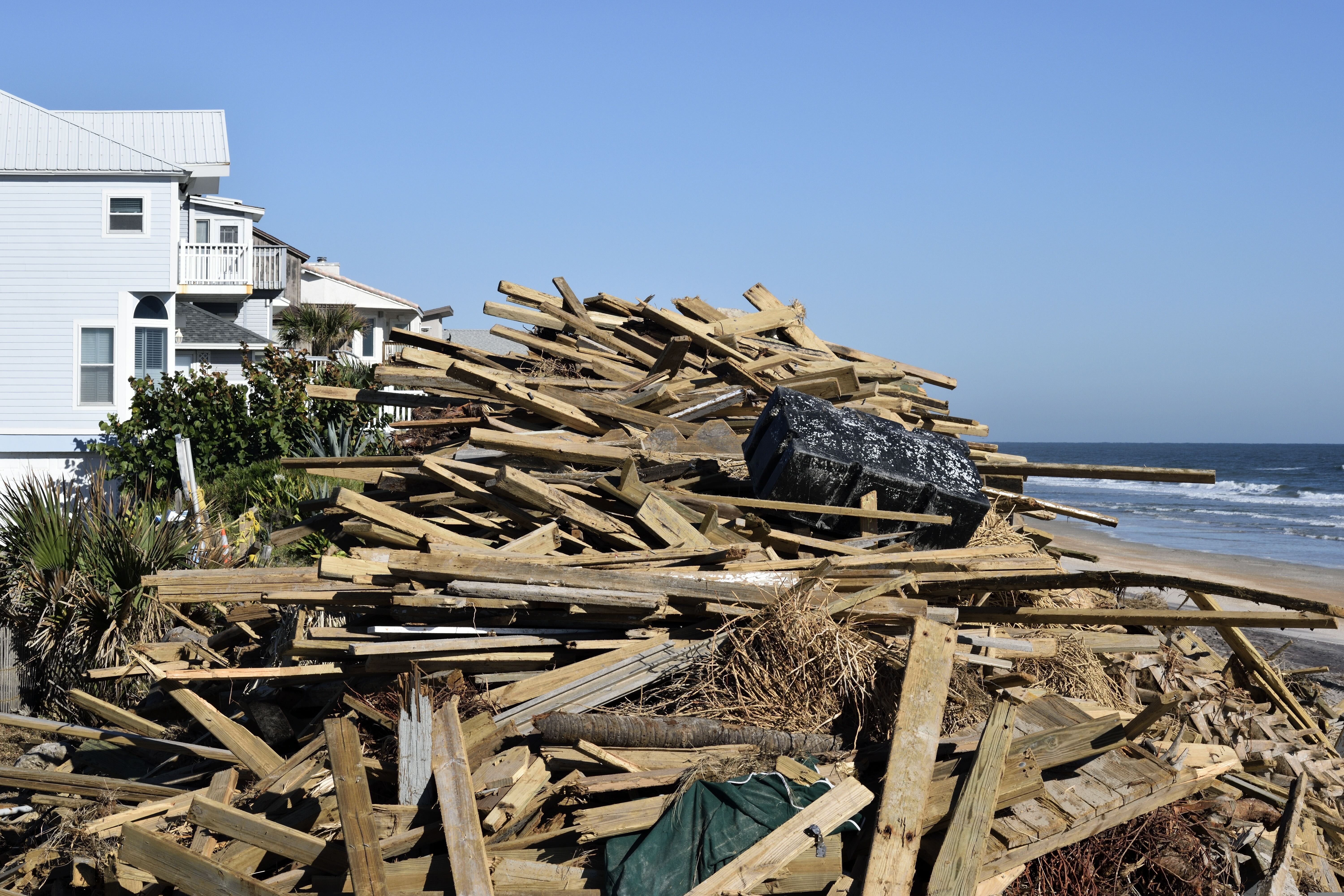 Storm damage debris piled near coastal home showing impact of severe weather on construction materials