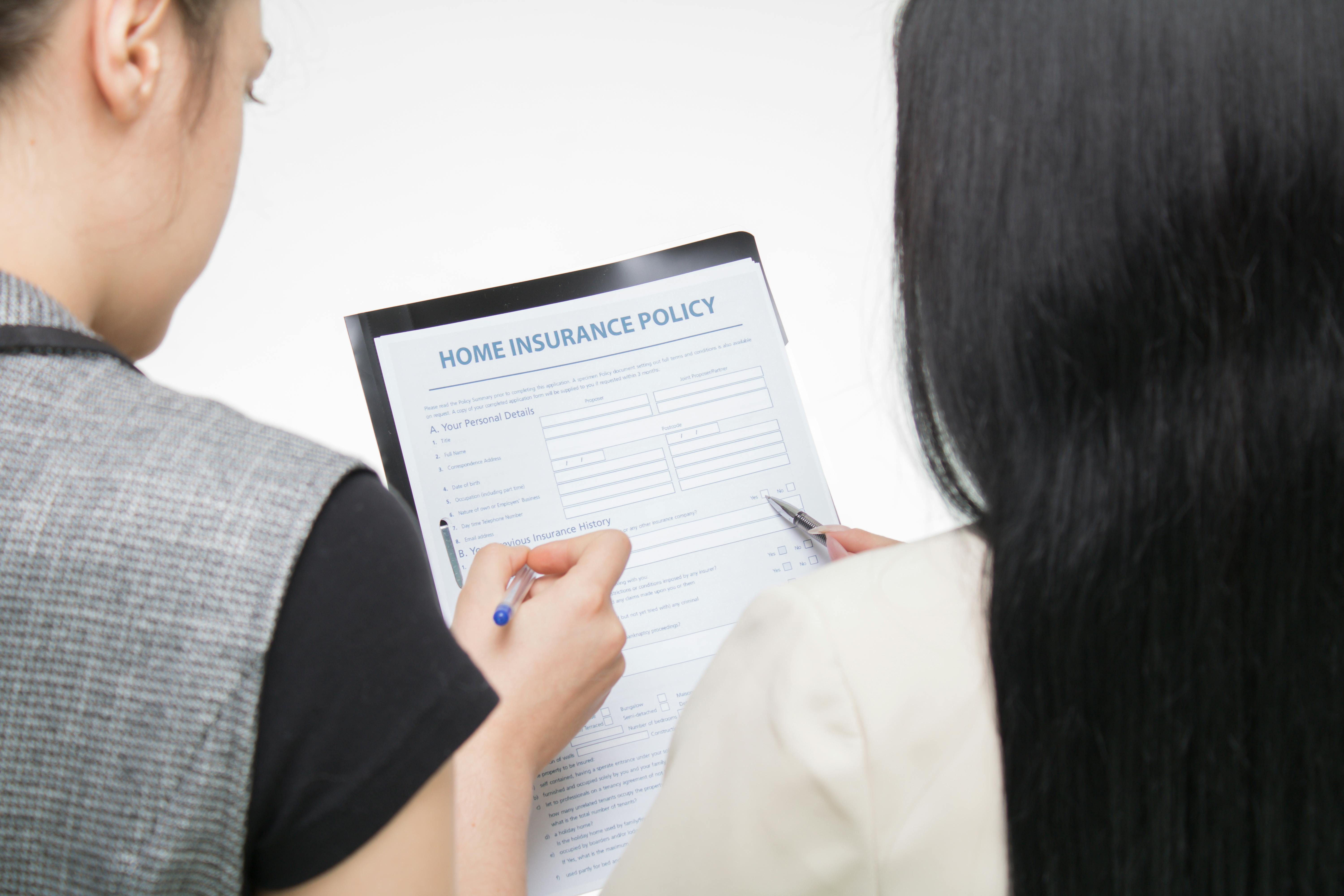 Two people reviewing a home insurance policy form together, discussing coverage details.