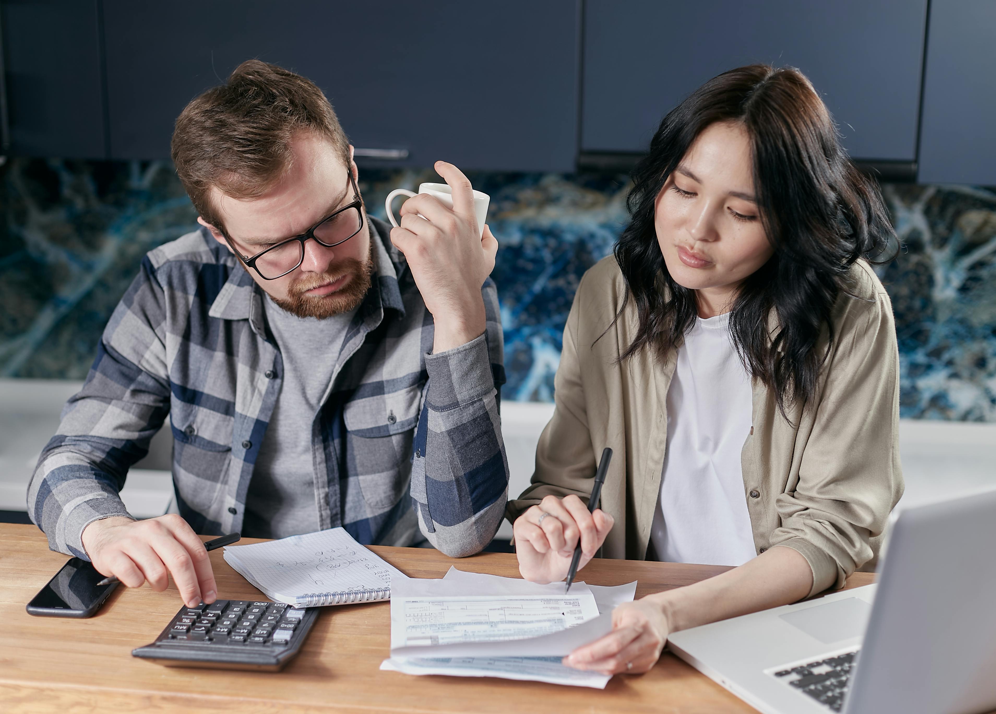Couple reviewing paperwork and using a calculator at home