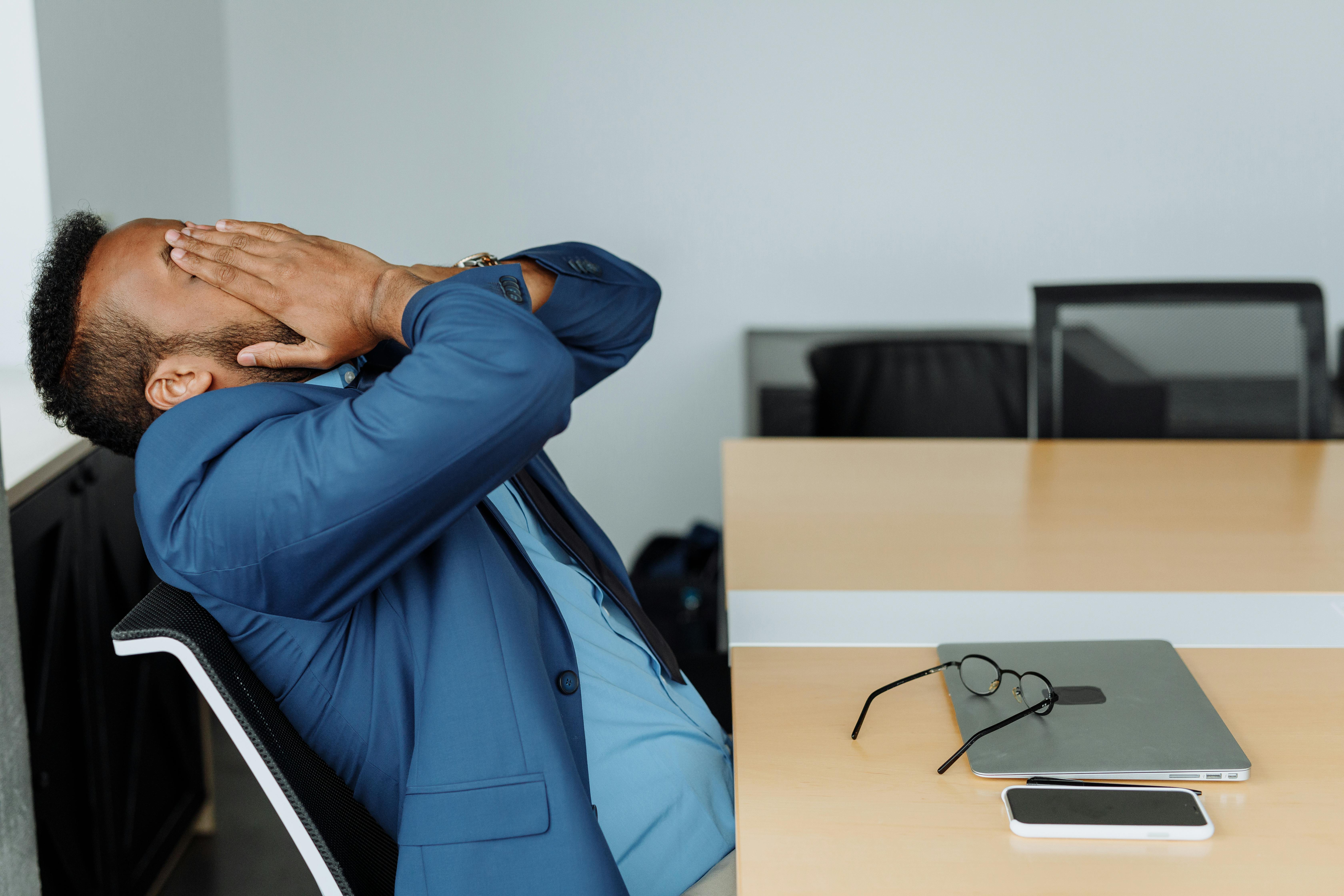 Business owner sitting at desk looking stressed over paperwork and insurance issues.