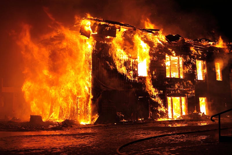 A large building completely on fire at night, showing how dangerous and fast battery fires can spread.