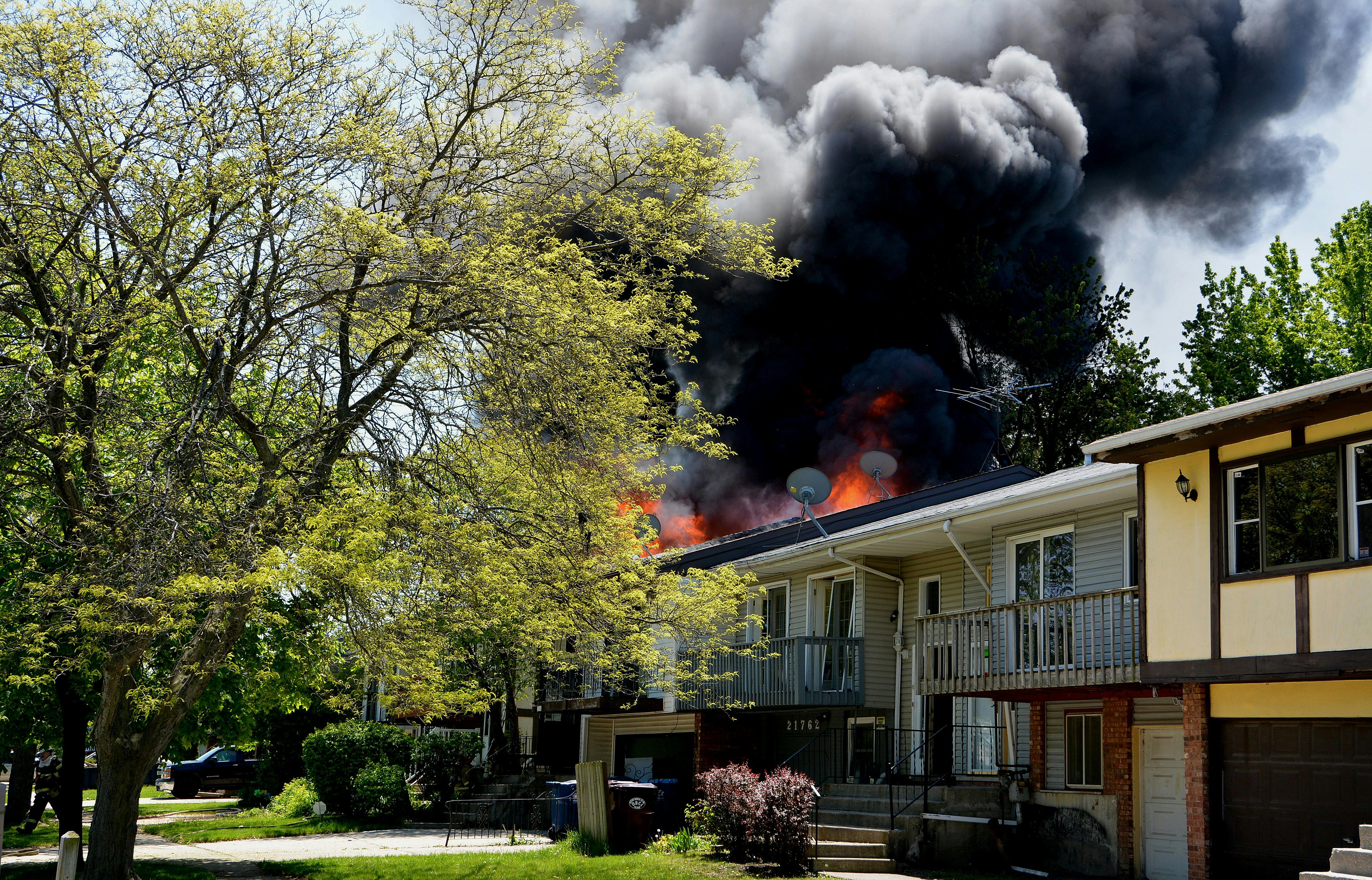 A house fire with thick black smoke and flames coming from the roof after a possible lithium-ion battery fire.