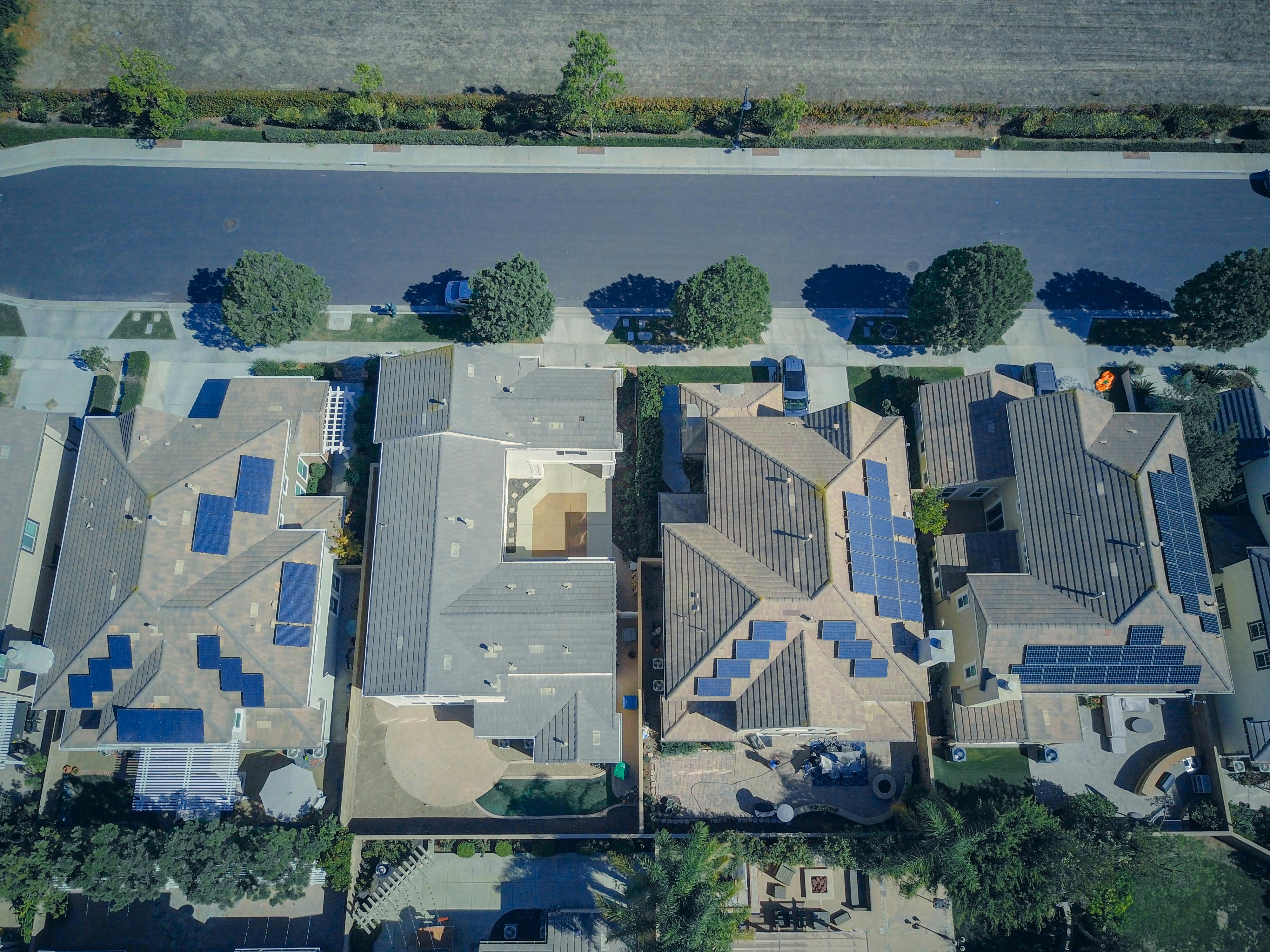 Aerial view of suburban homes with rooftop solar panels installed in a residential neighborhood.