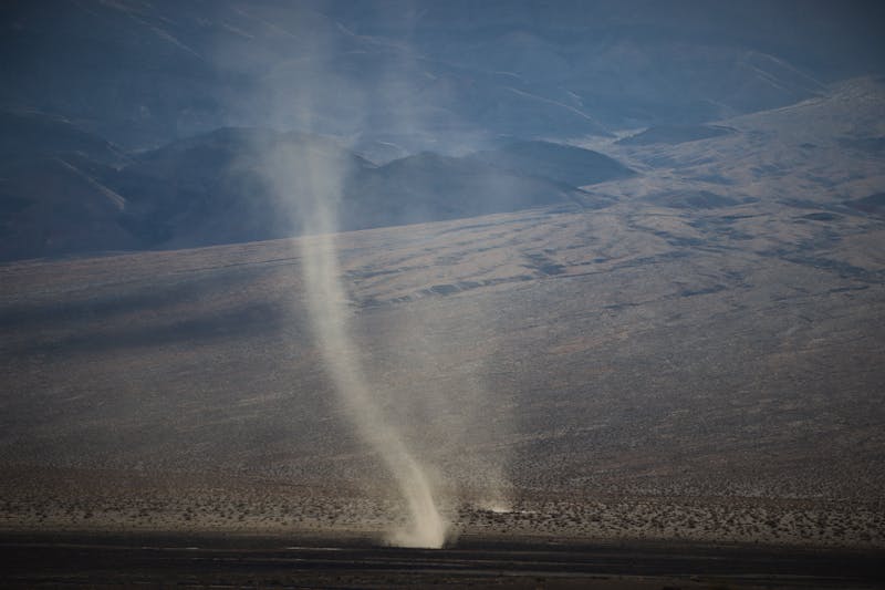 Large tornado moving across an open landscape during a severe weather outbreak with damaging winds and storm conditions.