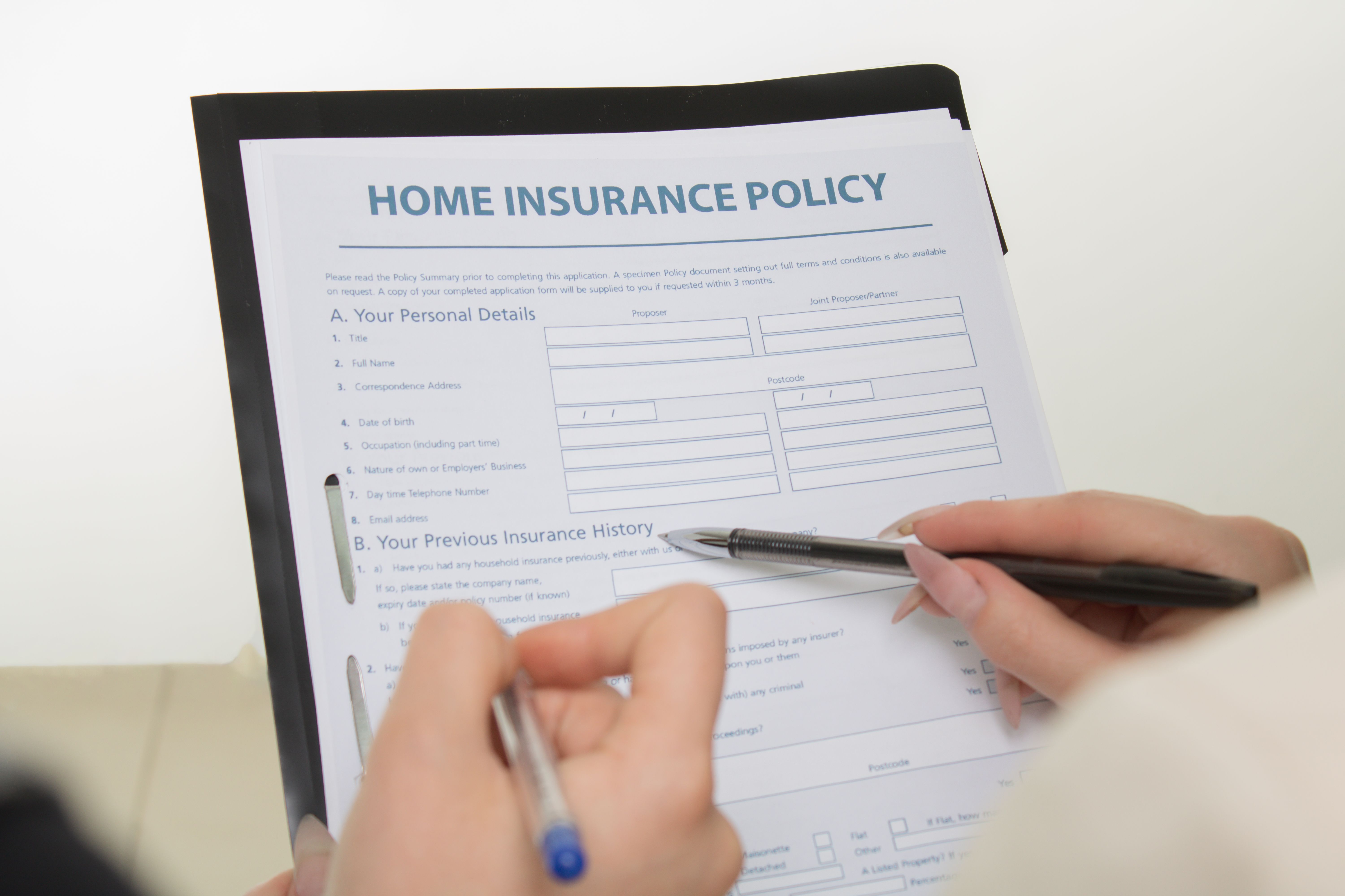 Person reviewing a home insurance policy document with a pen.