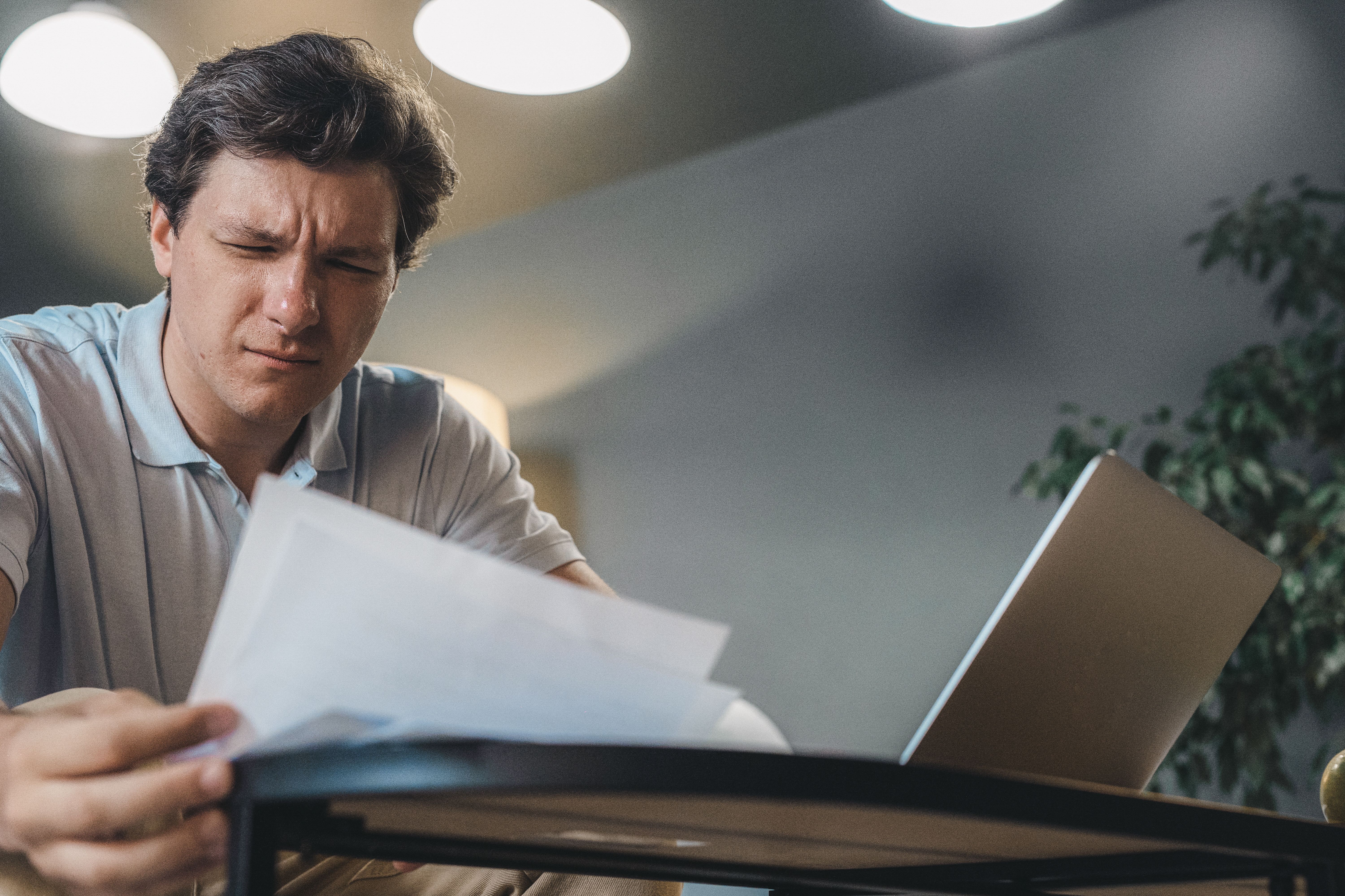 Concerned homeowner reviewing insurance claim paperwork beside a laptop.