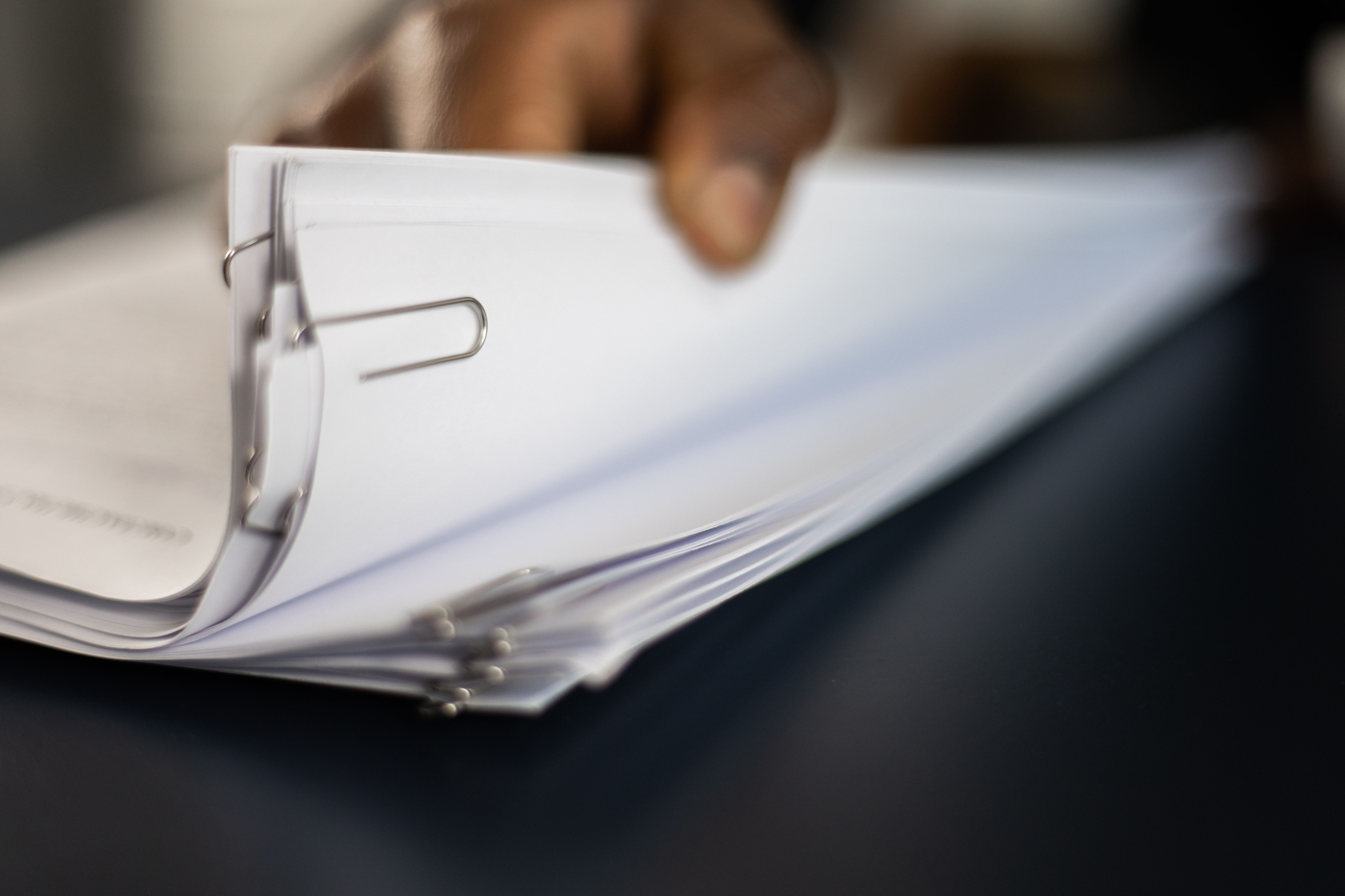 Close-up of a person reviewing organized home insurance claim documents in a binder.