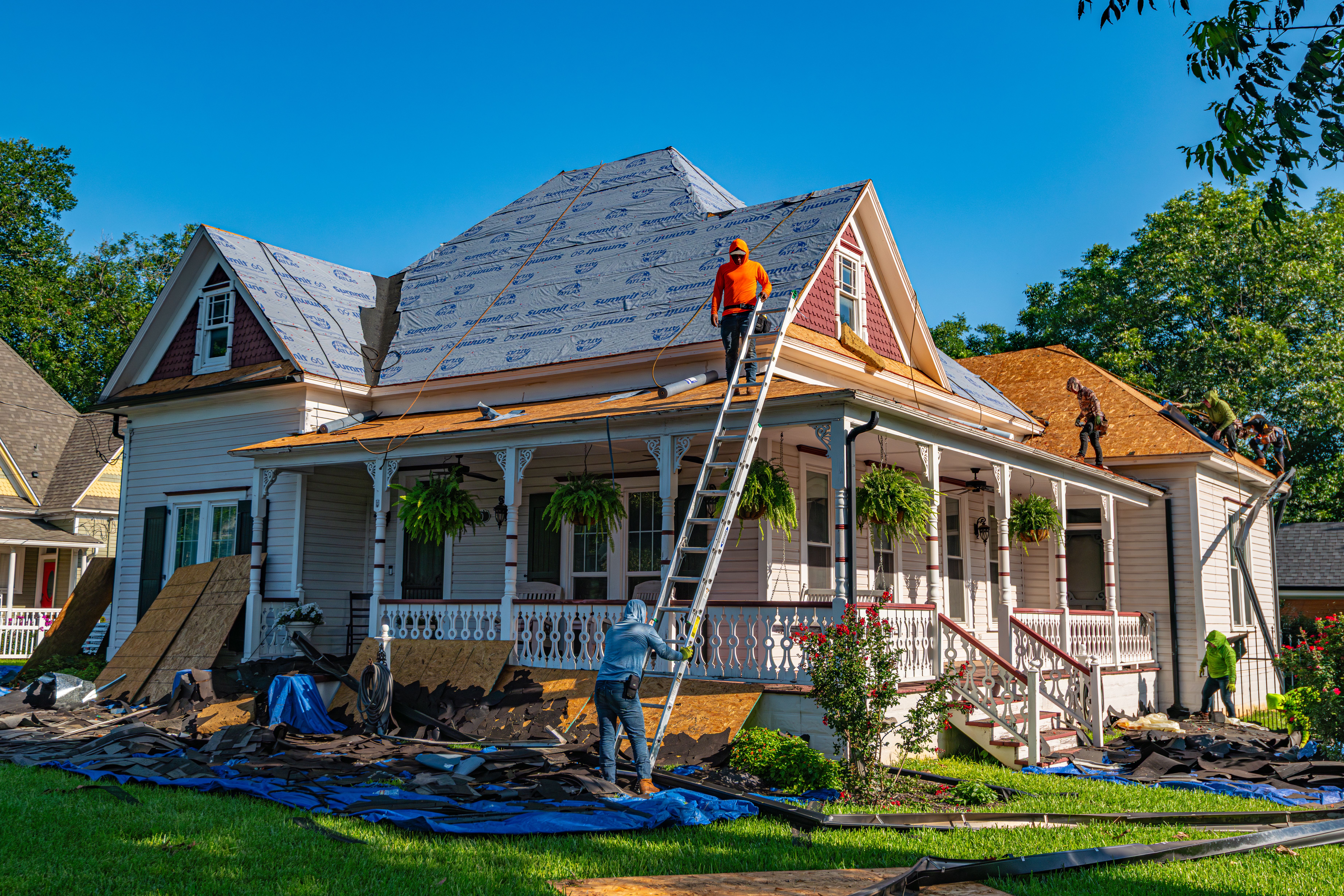Roofing contractors replacing a damaged residential roof after severe storm damage.