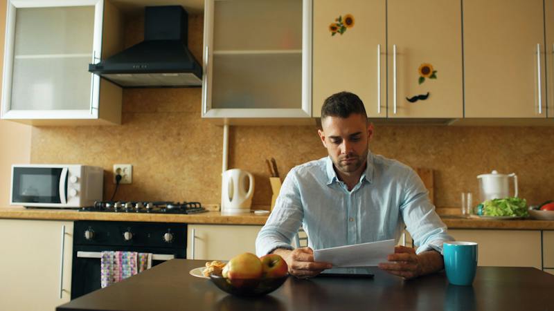 Man reviewing a document while sitting at his kitchen table