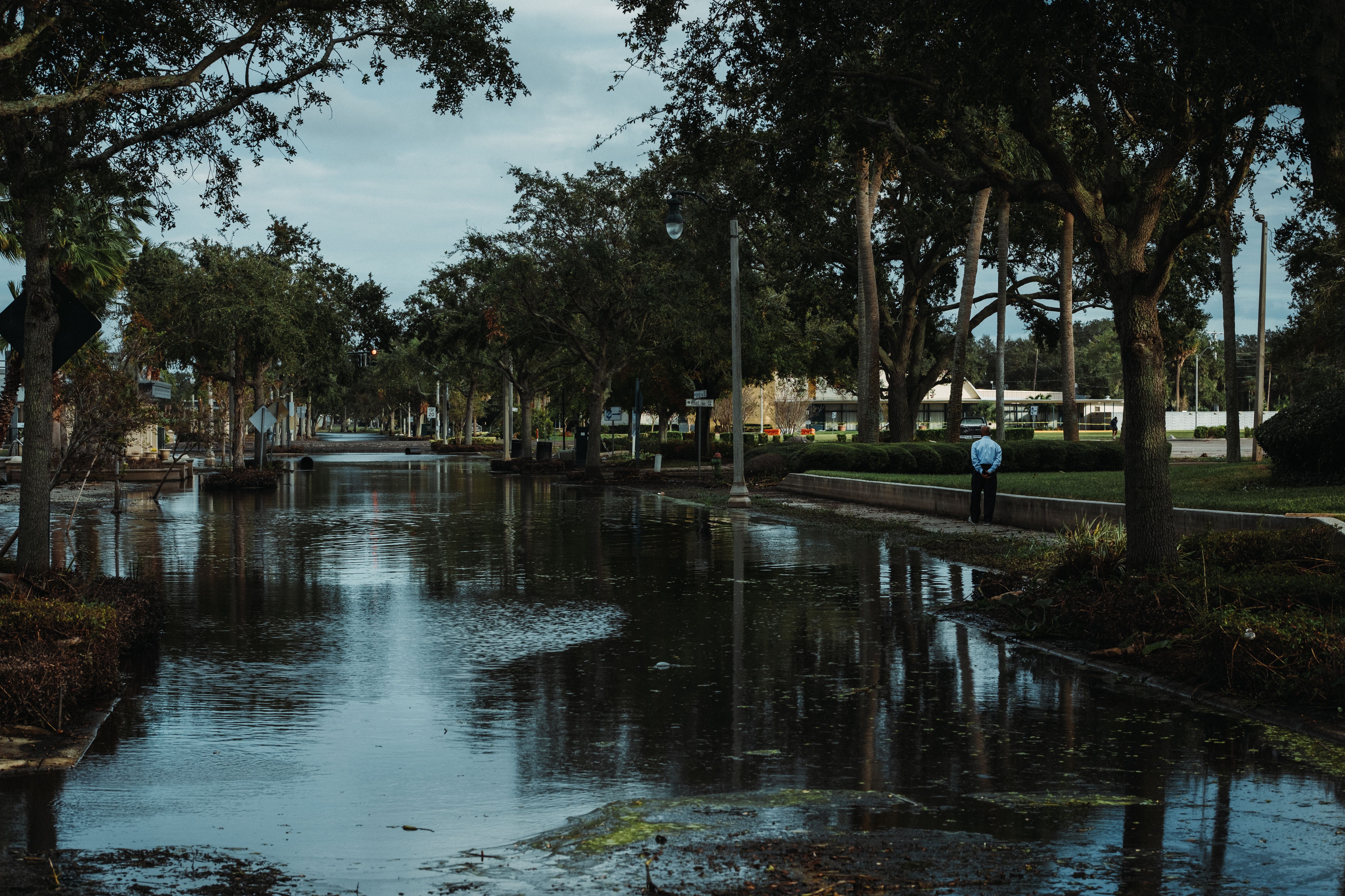 Flooded street surrounded by trees following hurricane storm damage in a Florida neighborhood.