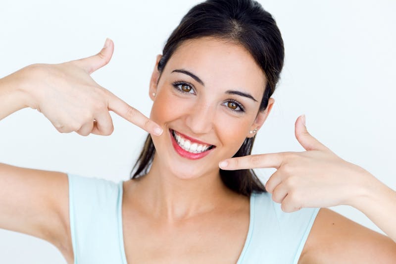 woman smiling while pointing to her teeth