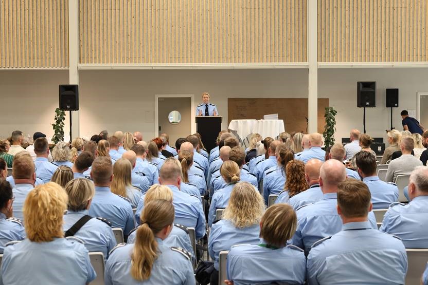 På billedet ses en masse fængselsbetjente sidde på rad og række med ryggen til kameraet. De kigger på kriminalforsorgens direktør Ina Eliasen, som står på en talerstol.