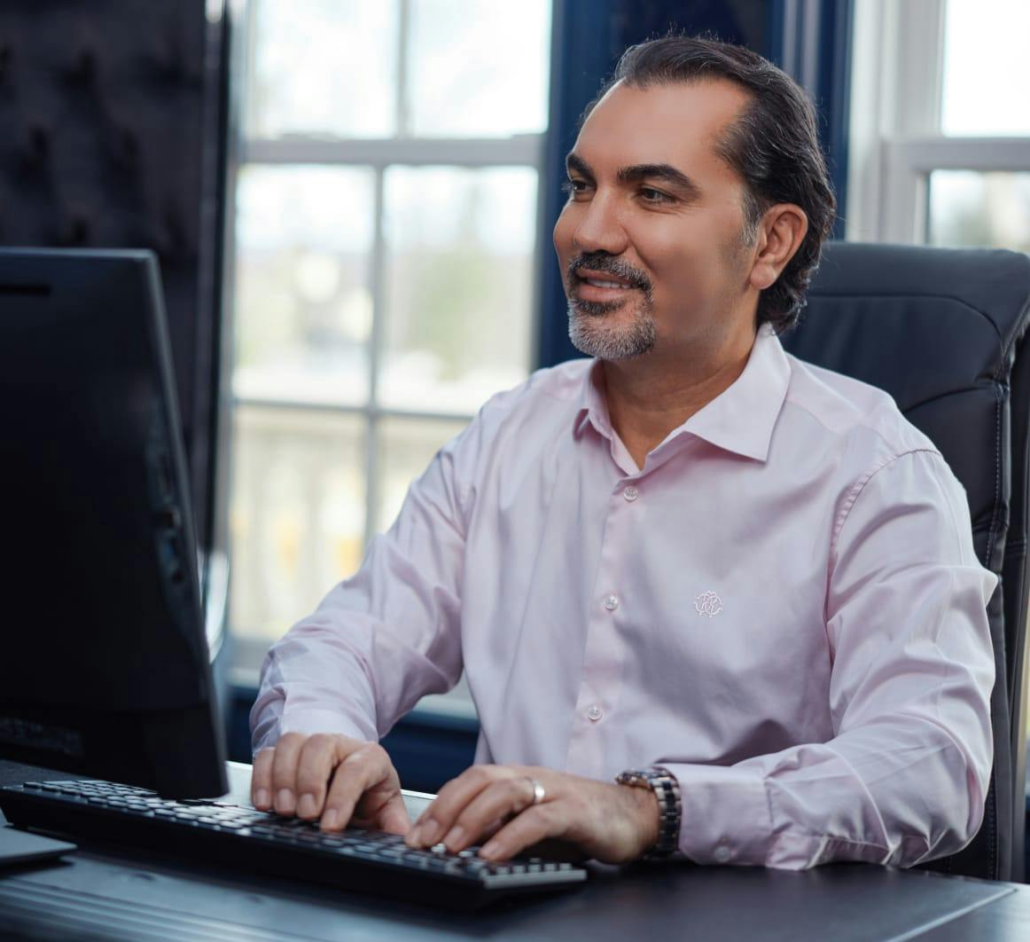 Dr. Aydin sitting at a desk, typing on a computer keyboard
