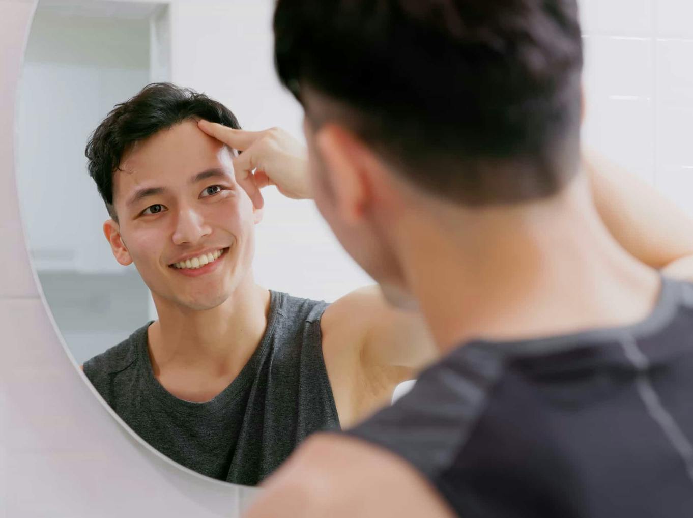 Man smiling while looking in mirror