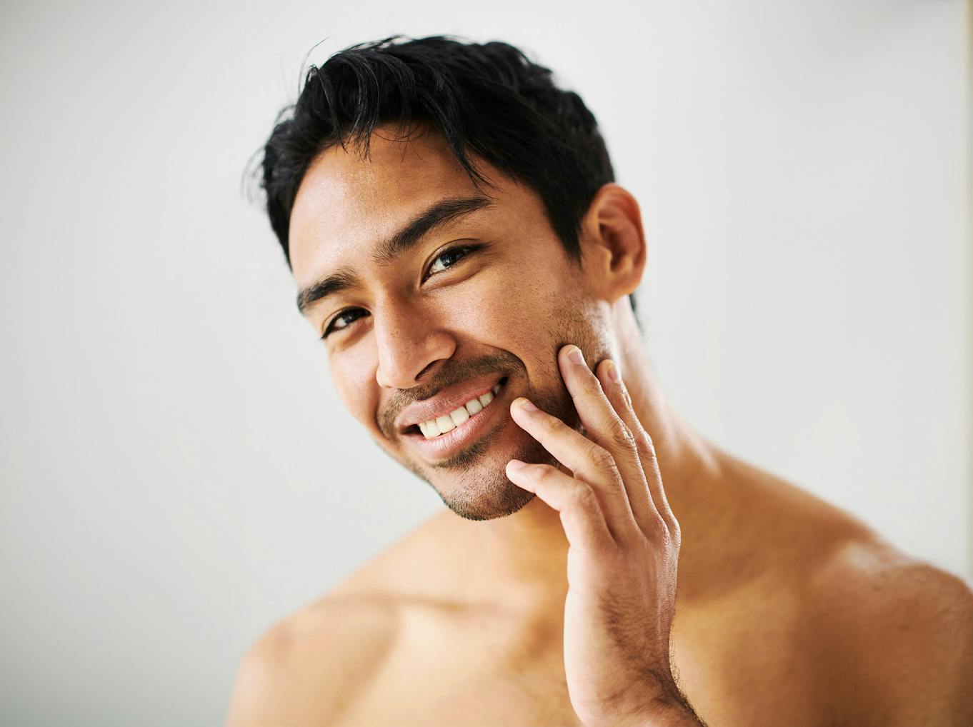 man touching his cheek and smiling