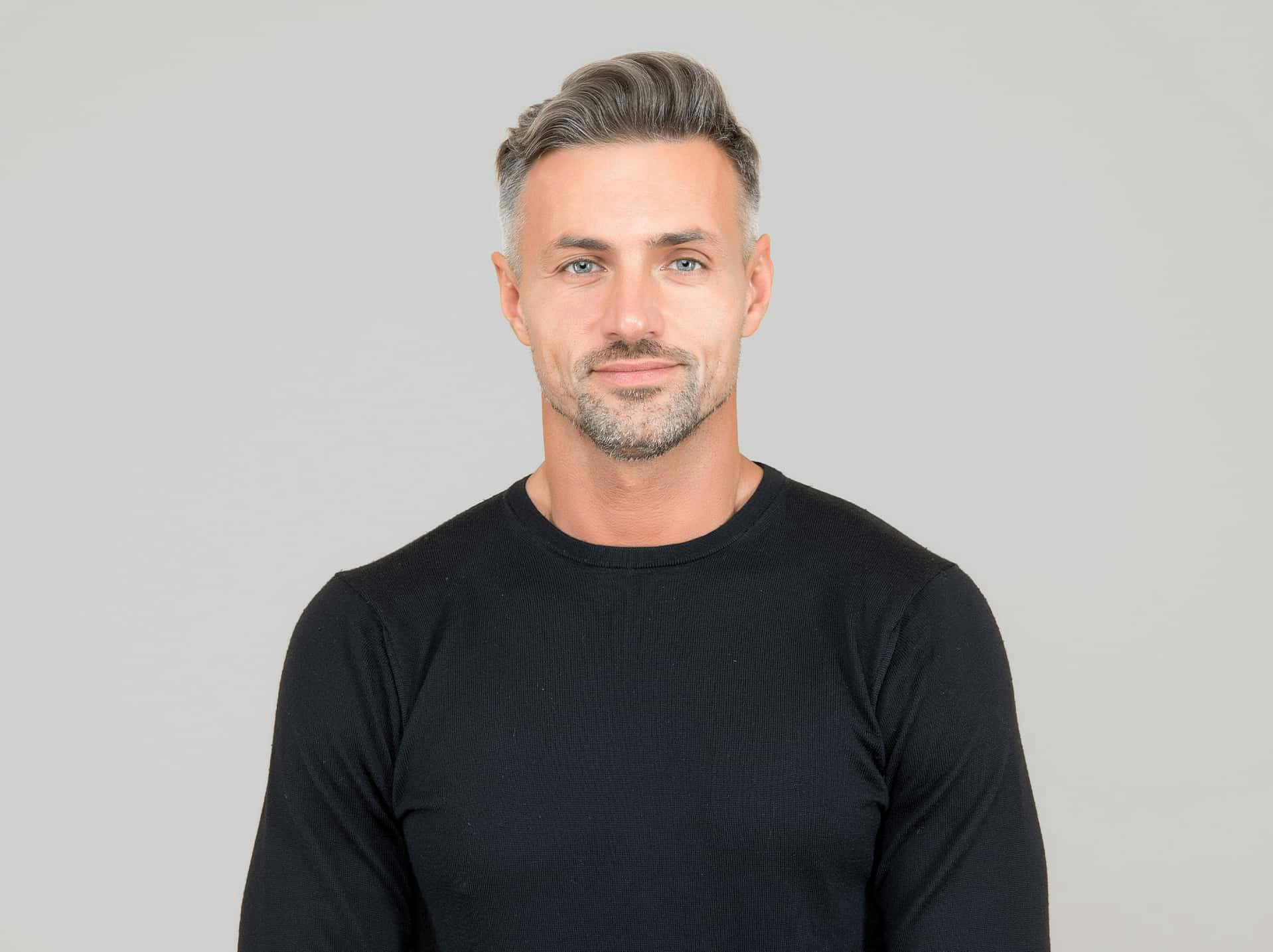 Man smiling agains a grey background